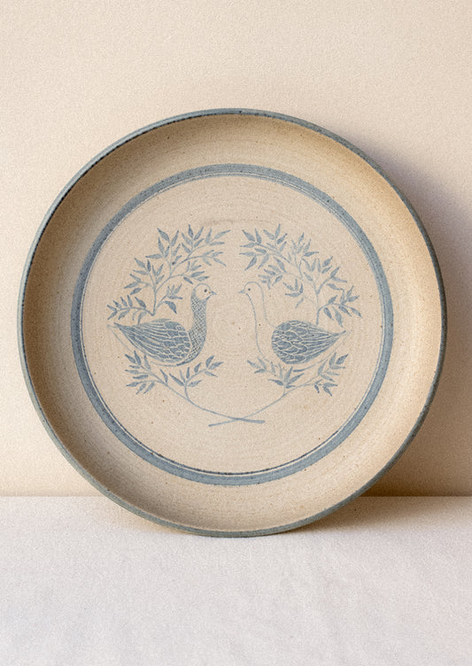 Ceramic plate with blue bird design on a beige background.