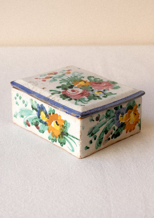 Decorative ceramic box with floral patterns on a plain background