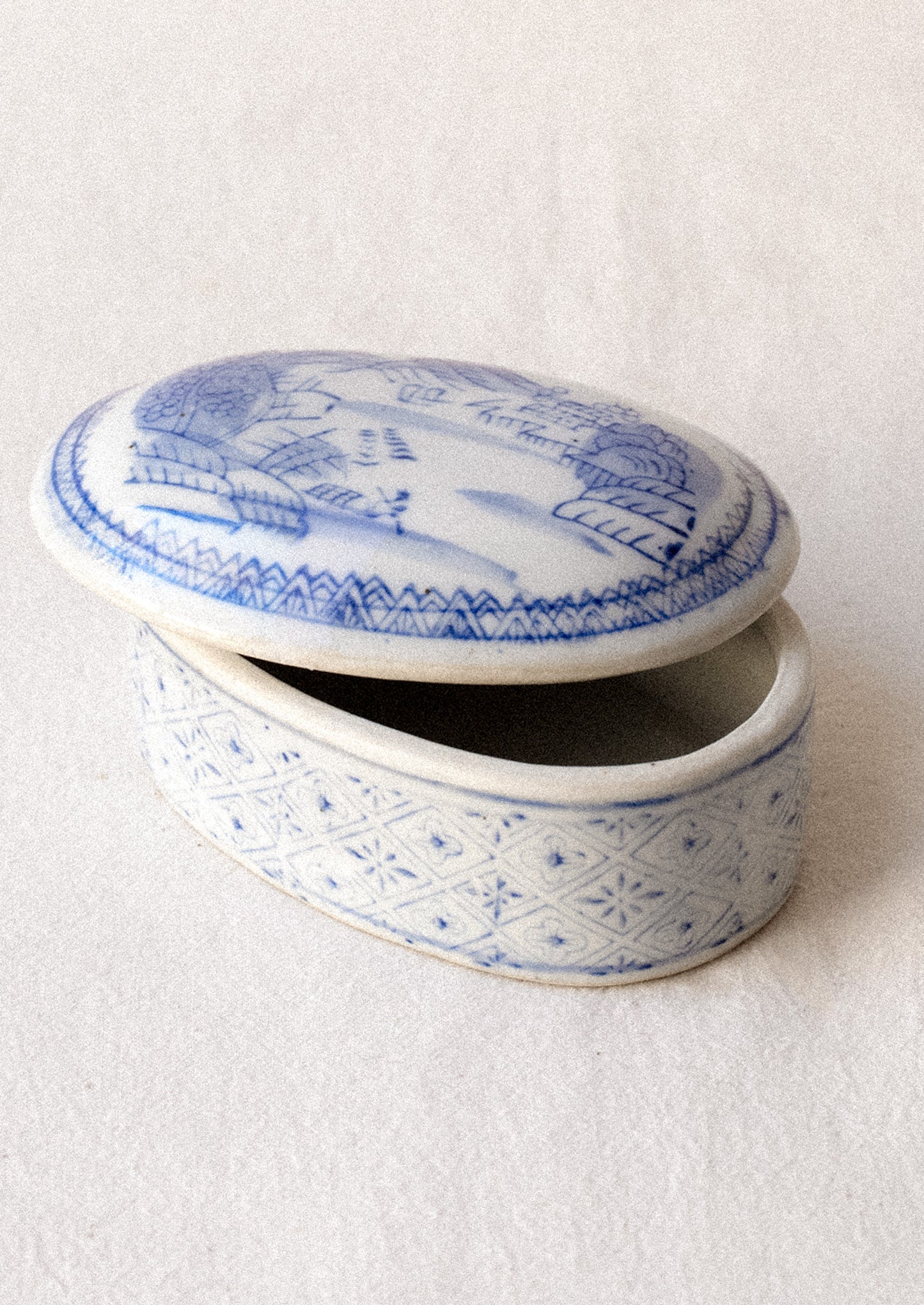 A blue and white chinoiserie patterned lidded ceramic box.