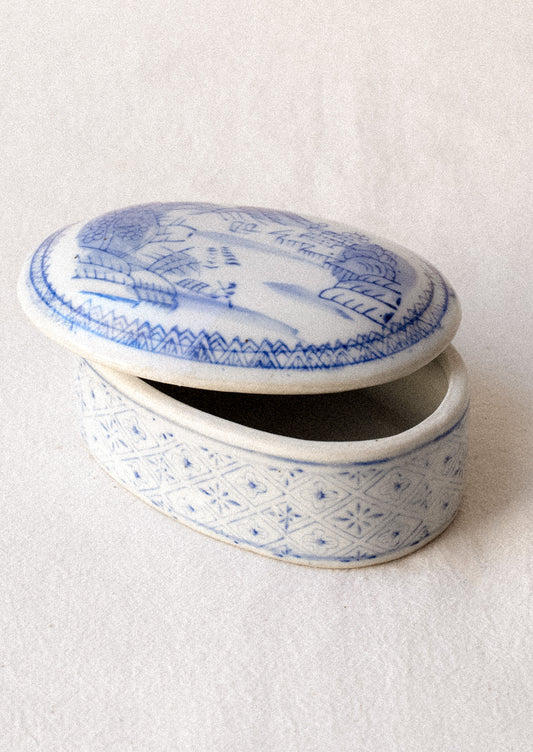 A blue and white chinoiserie patterned lidded ceramic box.