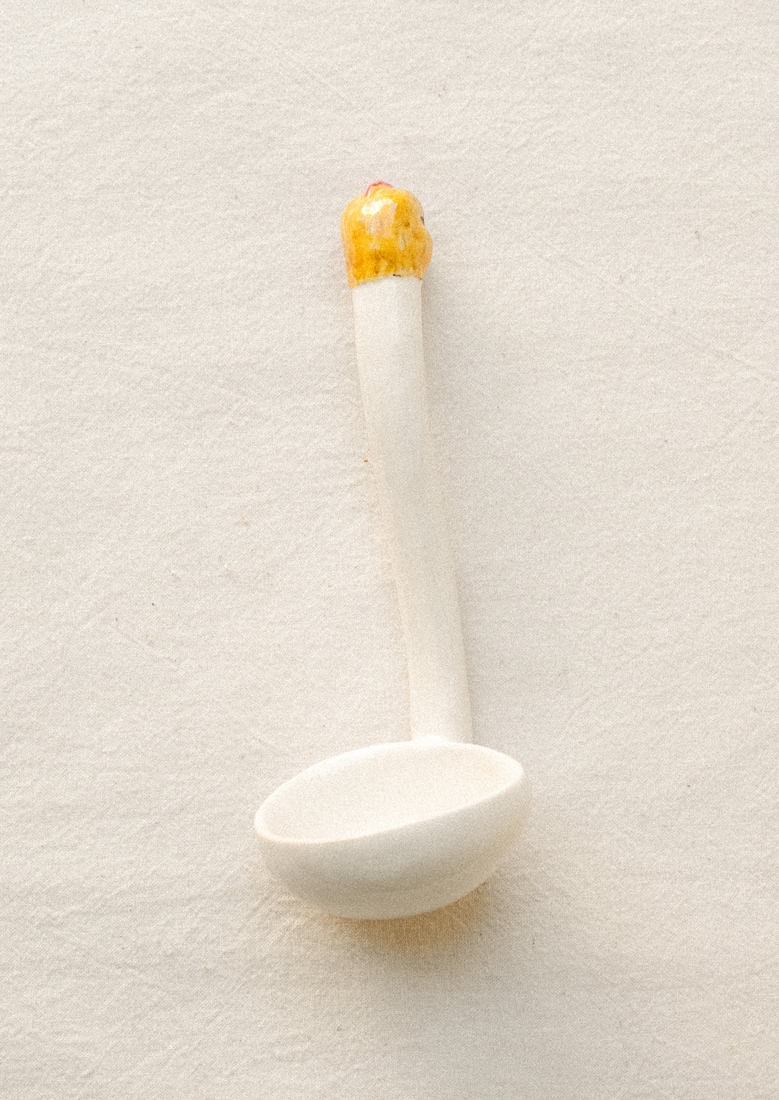 A small white ceramic ladle with chicken head on handle.