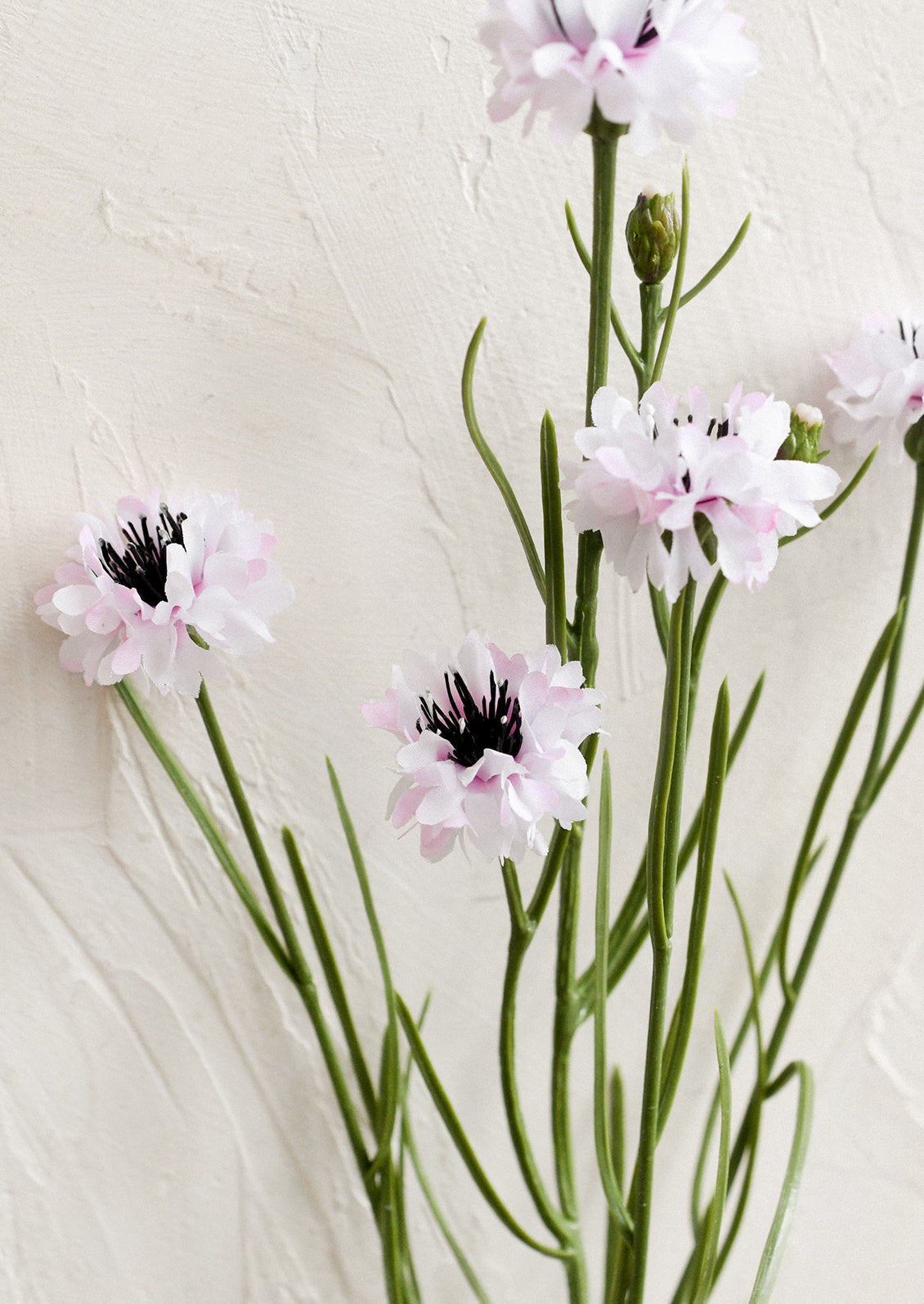 A faux floral spray depicting mini cornflower in pink.