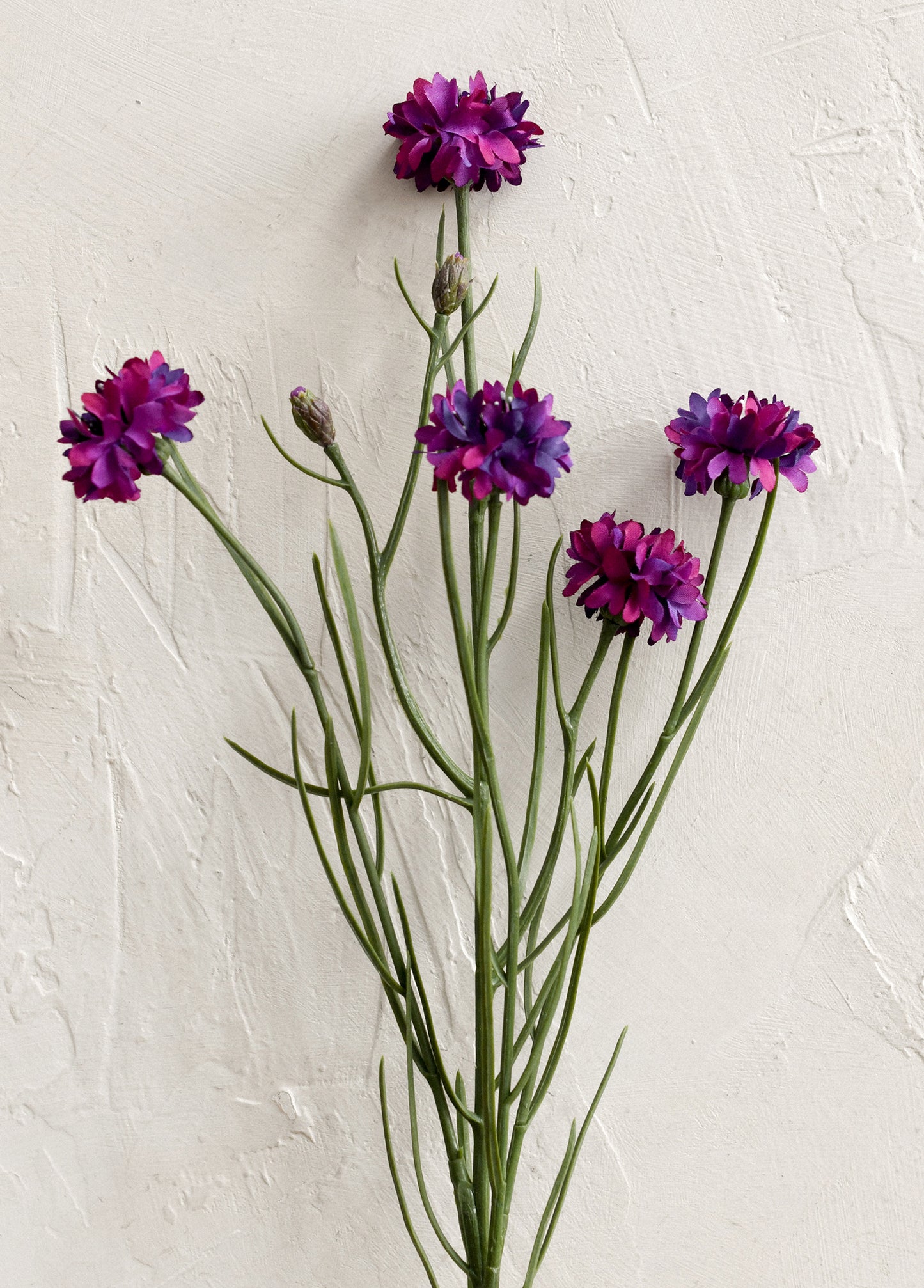 A faux floral spray depicting mini cornflower in purple.