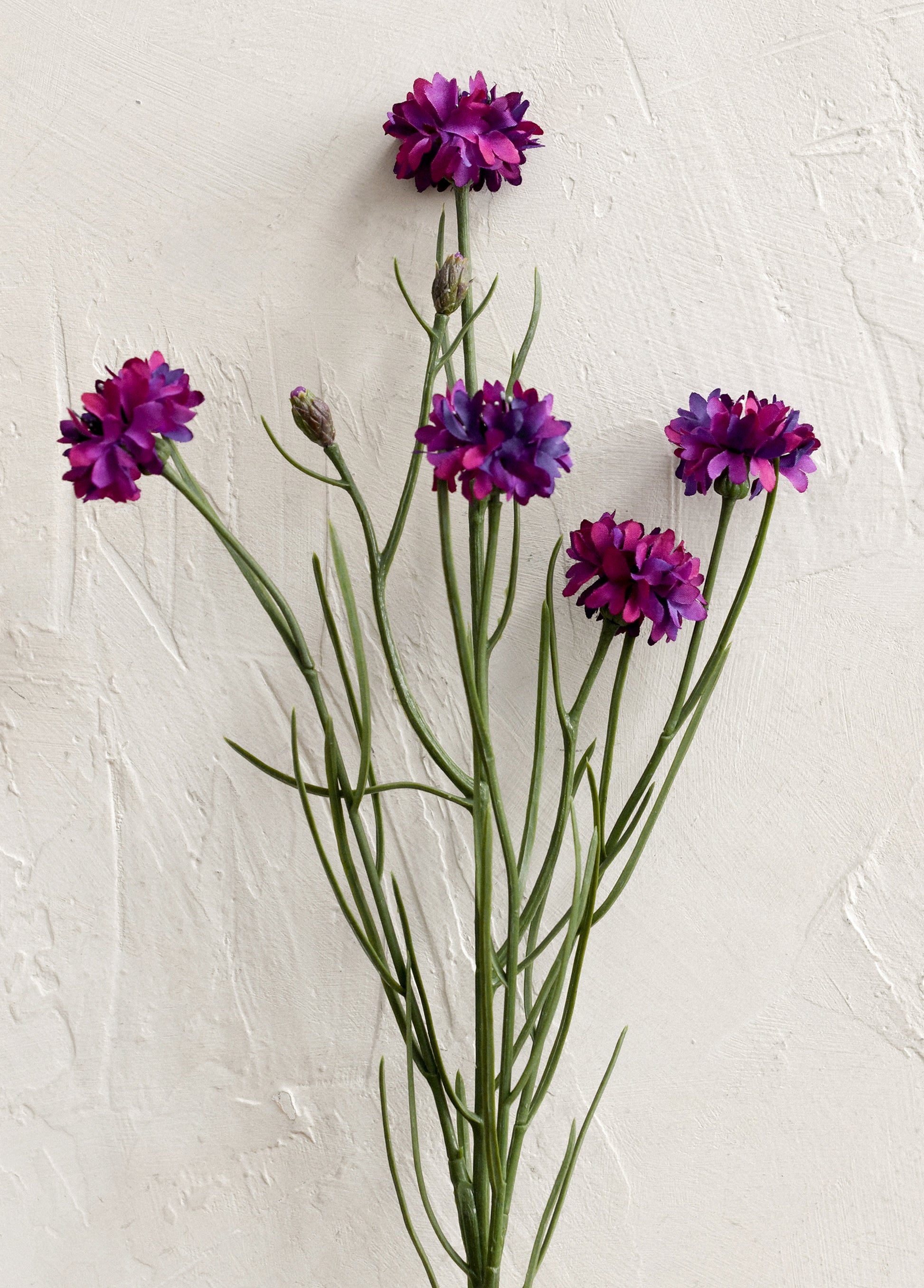 A faux floral spray depicting mini cornflower in purple.