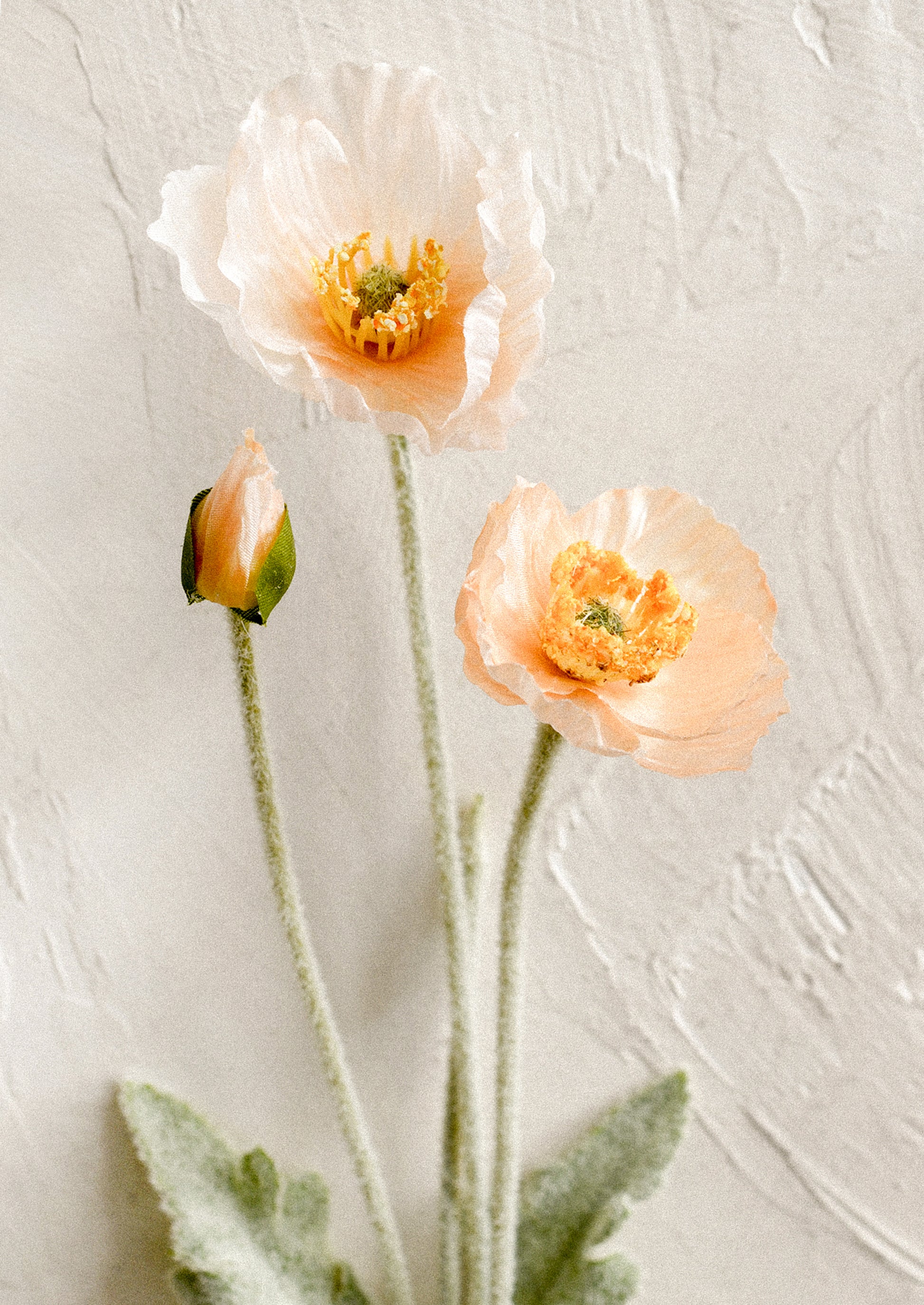 A faux floral stem depicting icelandic poppy flower in peach color.