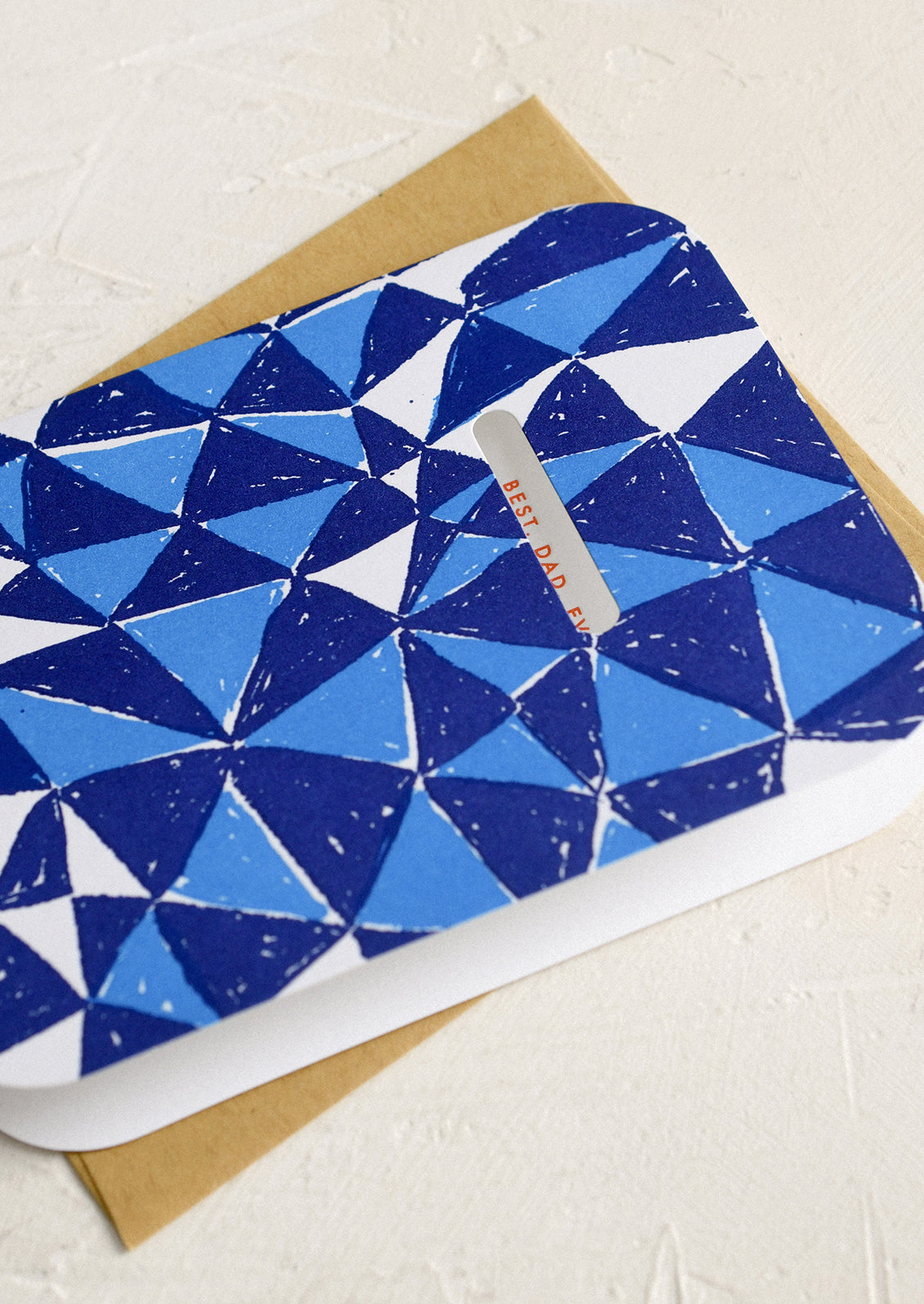 A blue triangle print card with cutout window revealing red lettering reading "Best. Dad. Ever.".