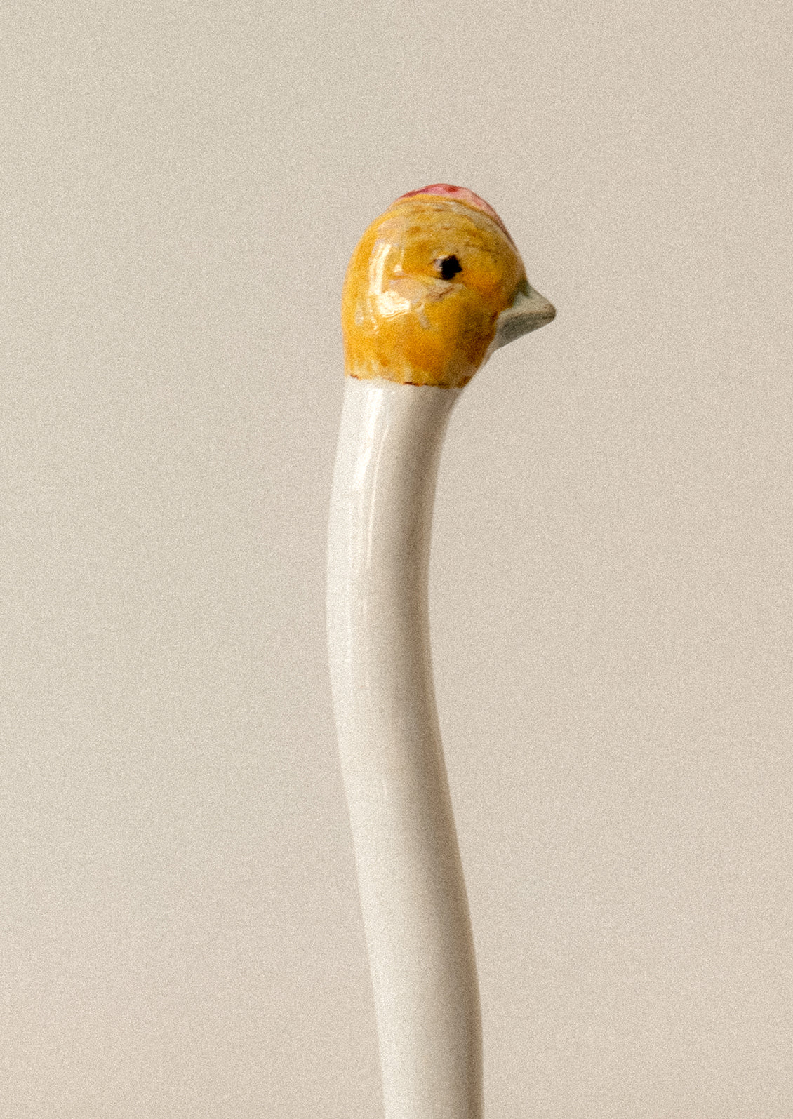 A small white ceramic ladle with chicken head on handle.
