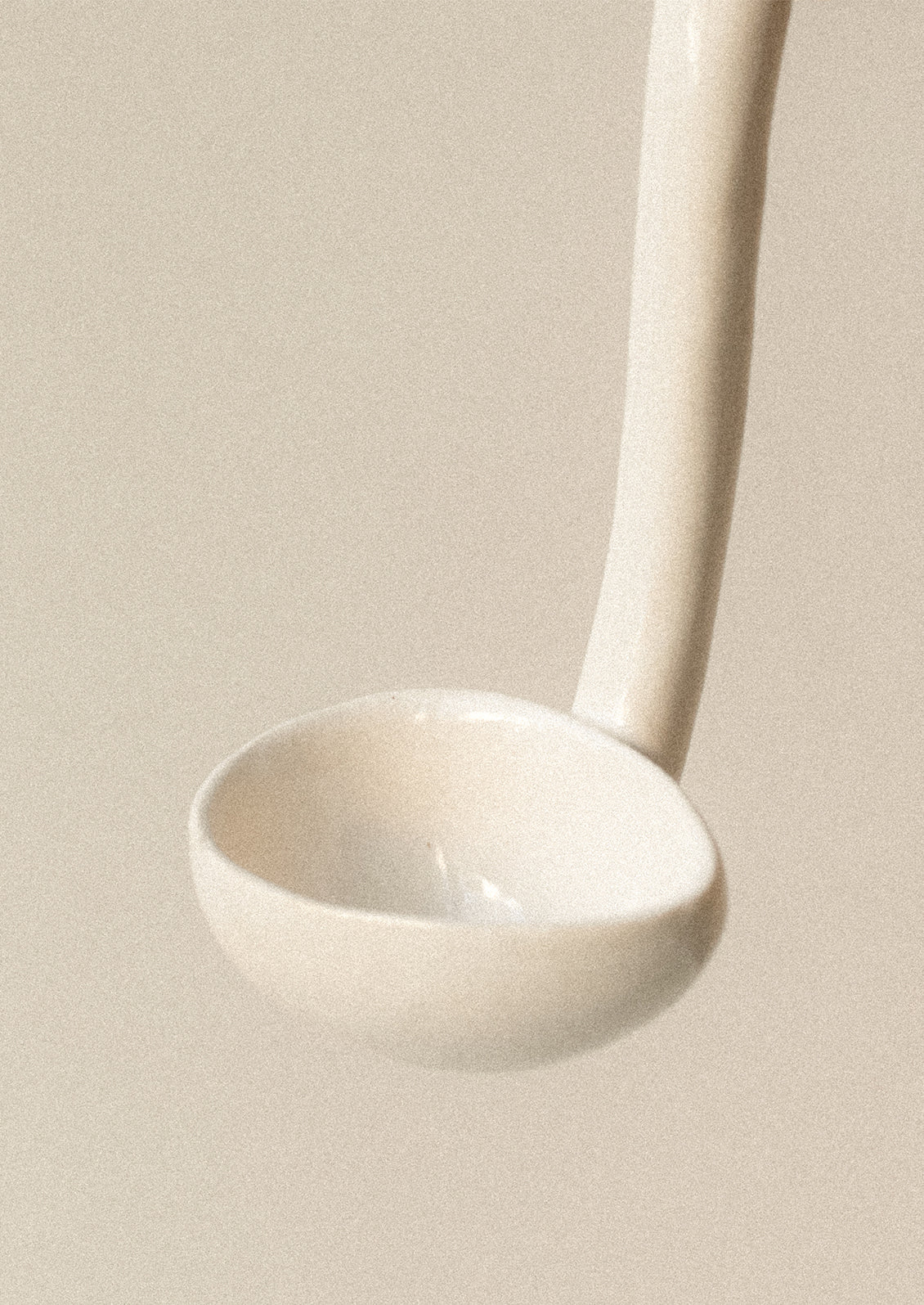A small white ceramic ladle with chicken head on handle.