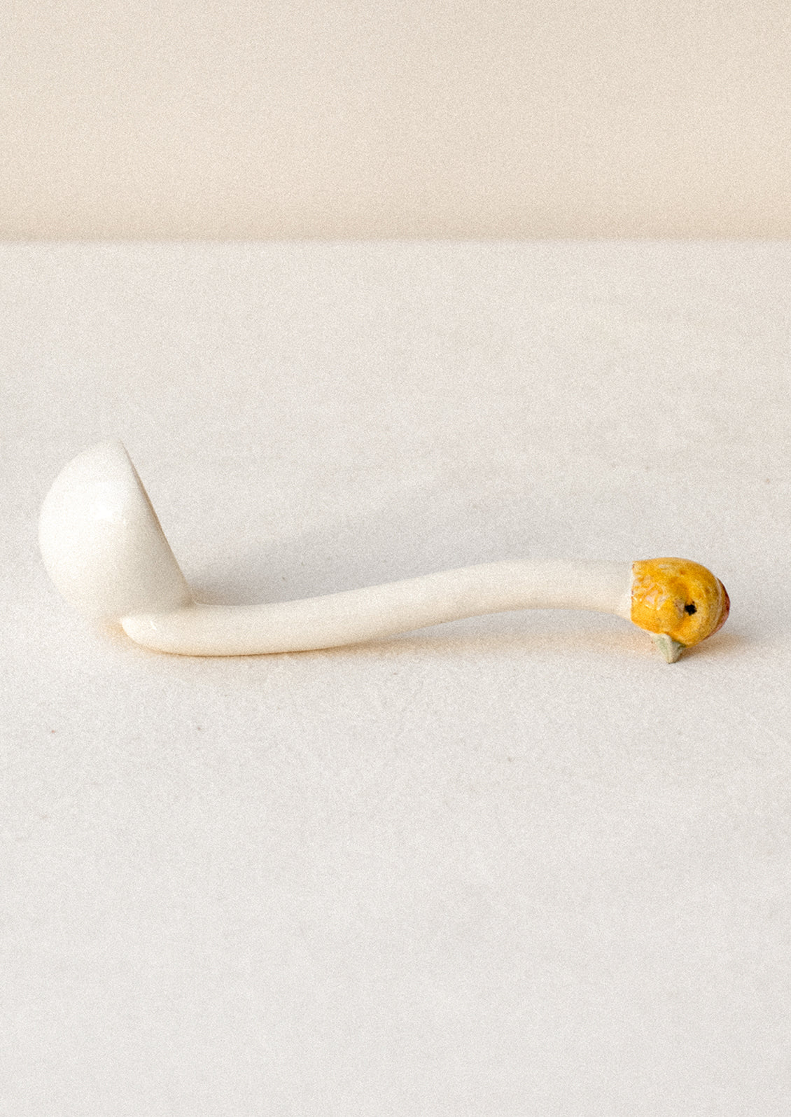 A small white ceramic ladle with chicken head on handle.