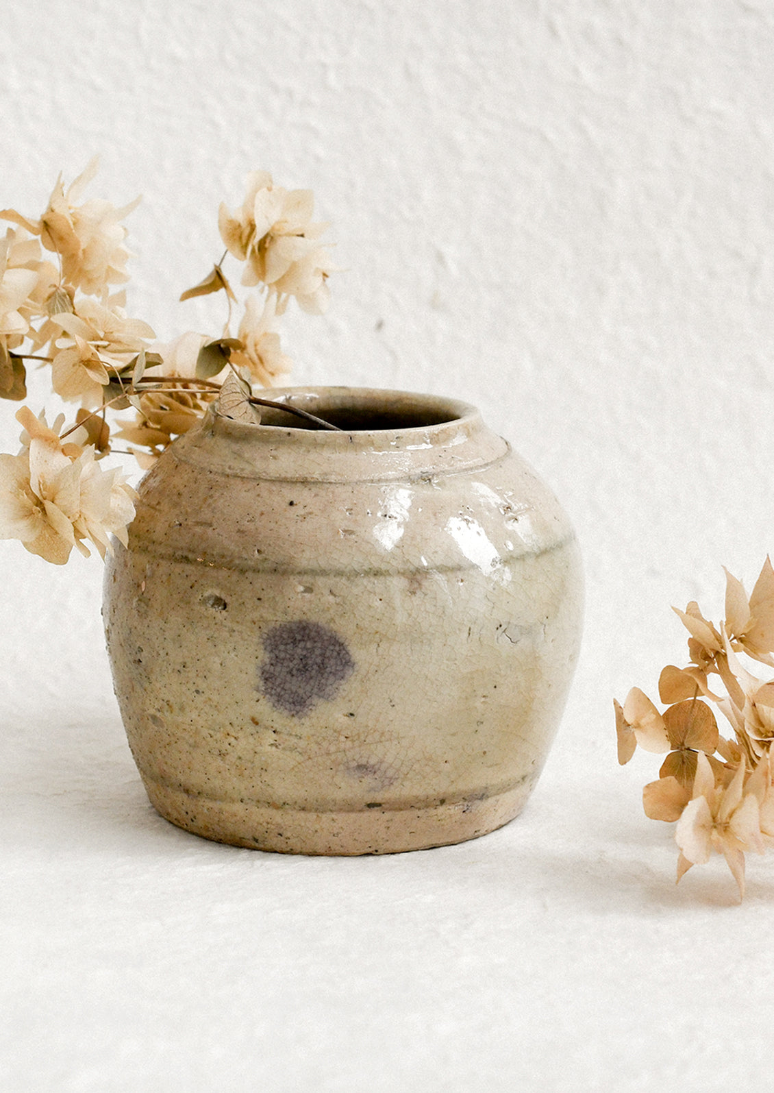 A small ironstone antique jar in greyish brown with heavy patina and soft stripe pattern.