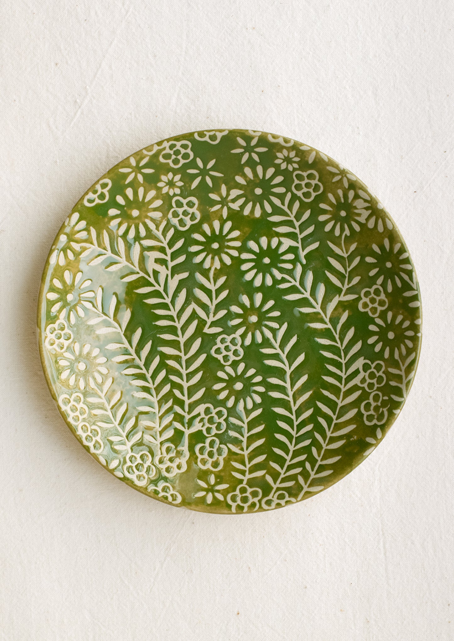 A small side plate with wax relief floral pattern in green and ivory.