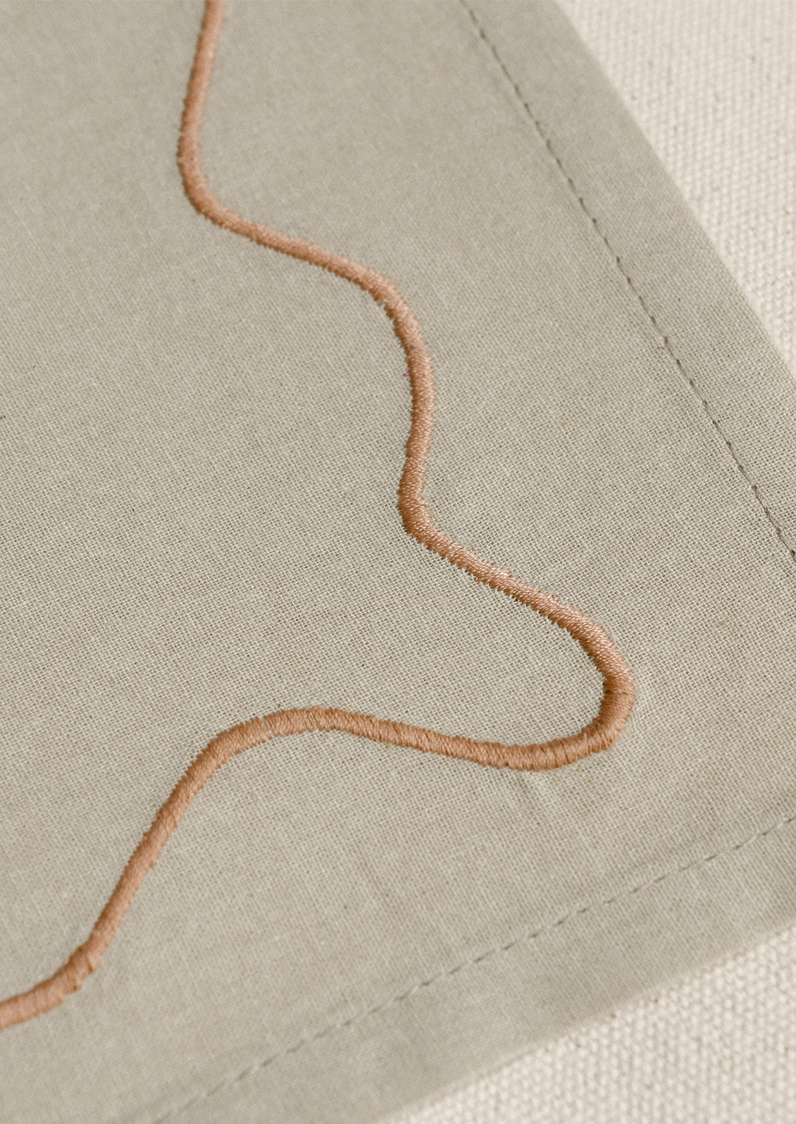 A tan placemat with peach squiggle border.