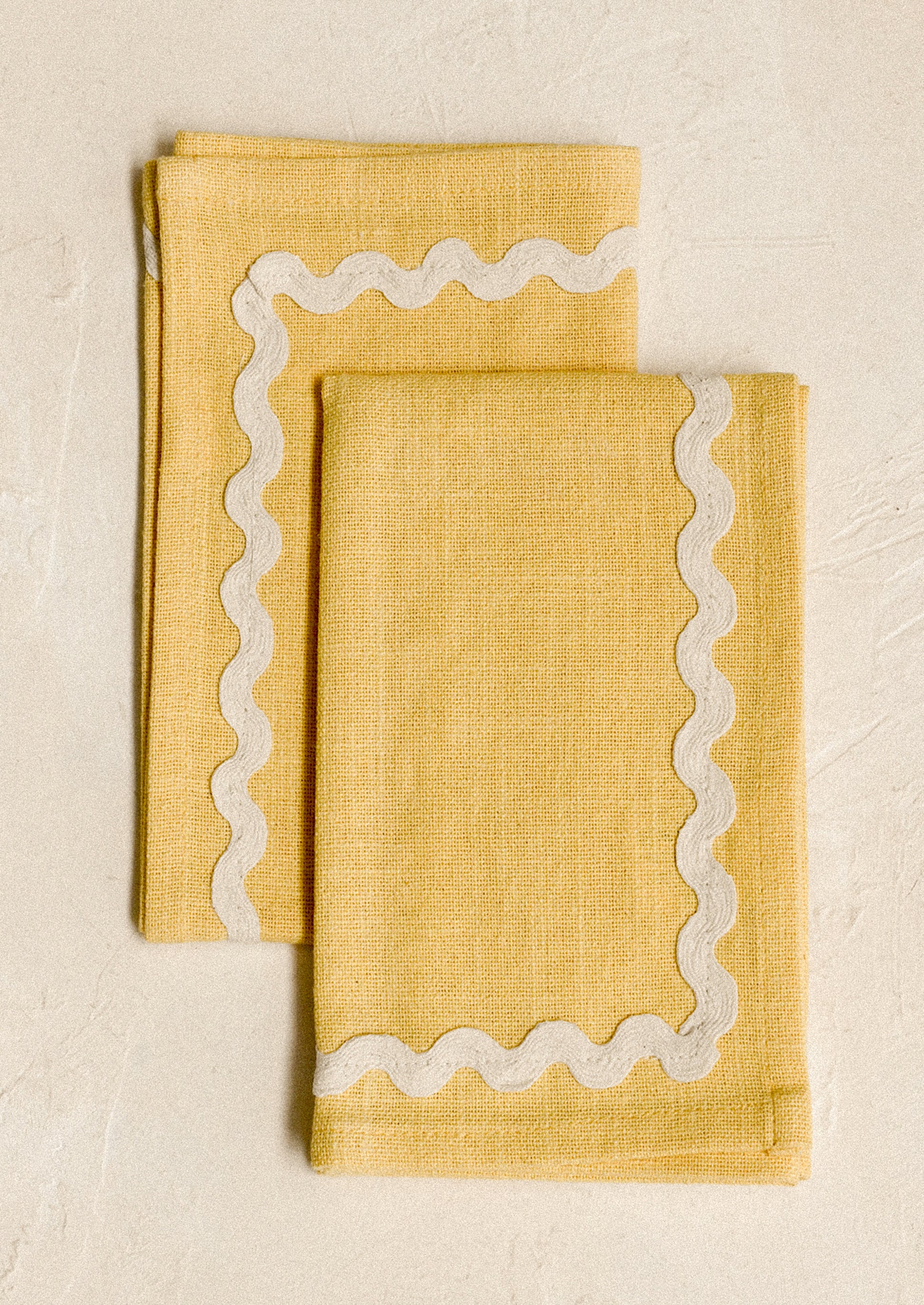 A pair of yellow napkins with white ricrac border.