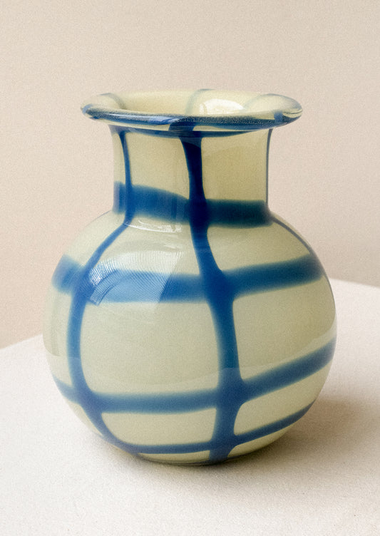 A glass vase with round shape, in yellow with painted blue gingham pattern.