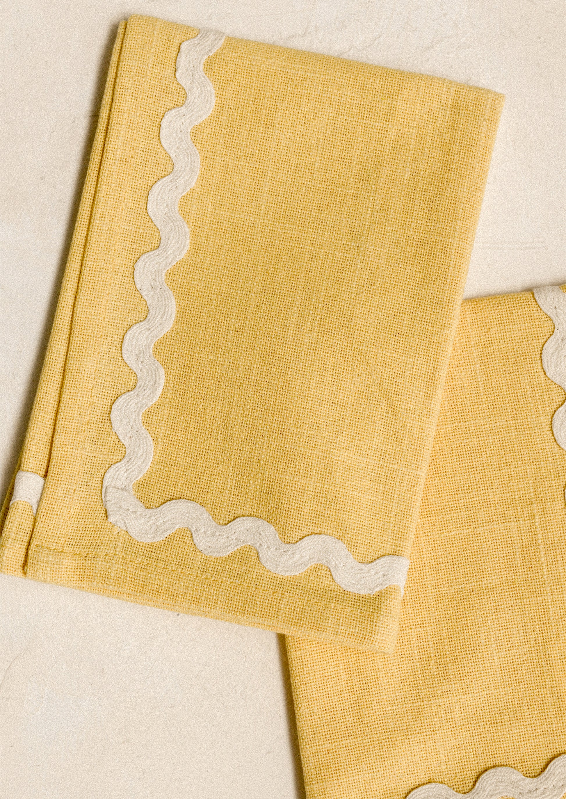 A pair of yellow napkins with white ricrac border.