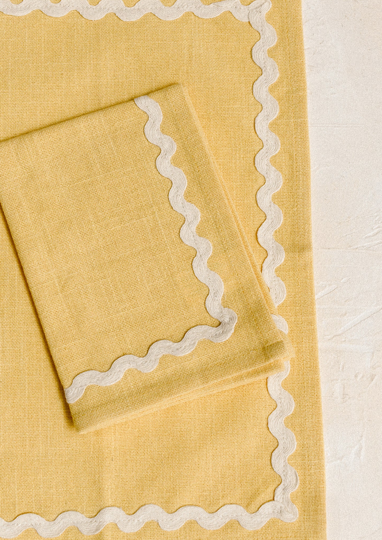 A pair of yellow napkins with white ricrac border.