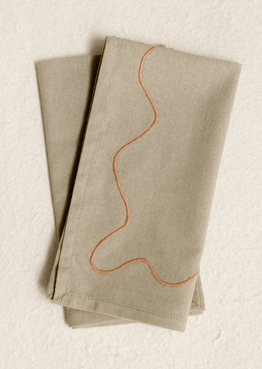 A pair of greige napkins with peach squiggle embroidery.