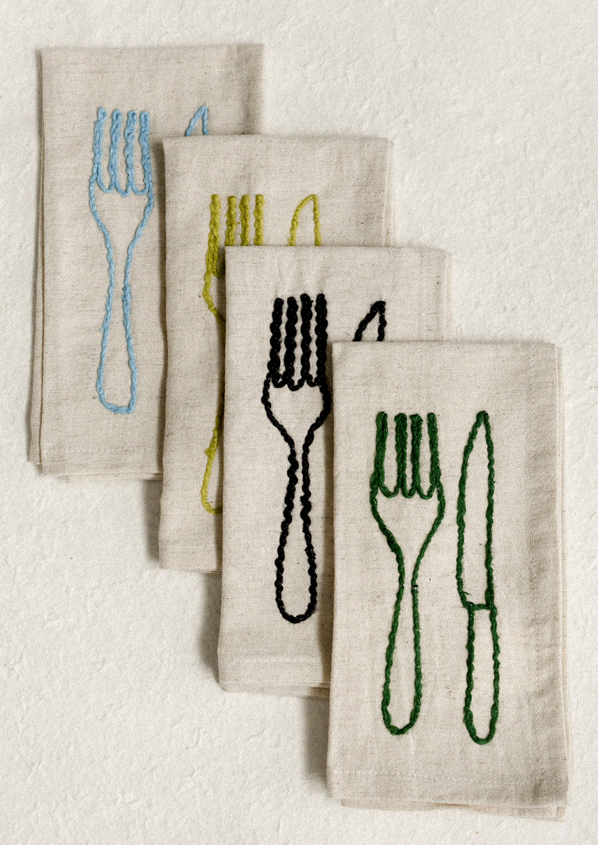 A set of natural linen napkins with embroidered fork and knife motif in assorted colors.