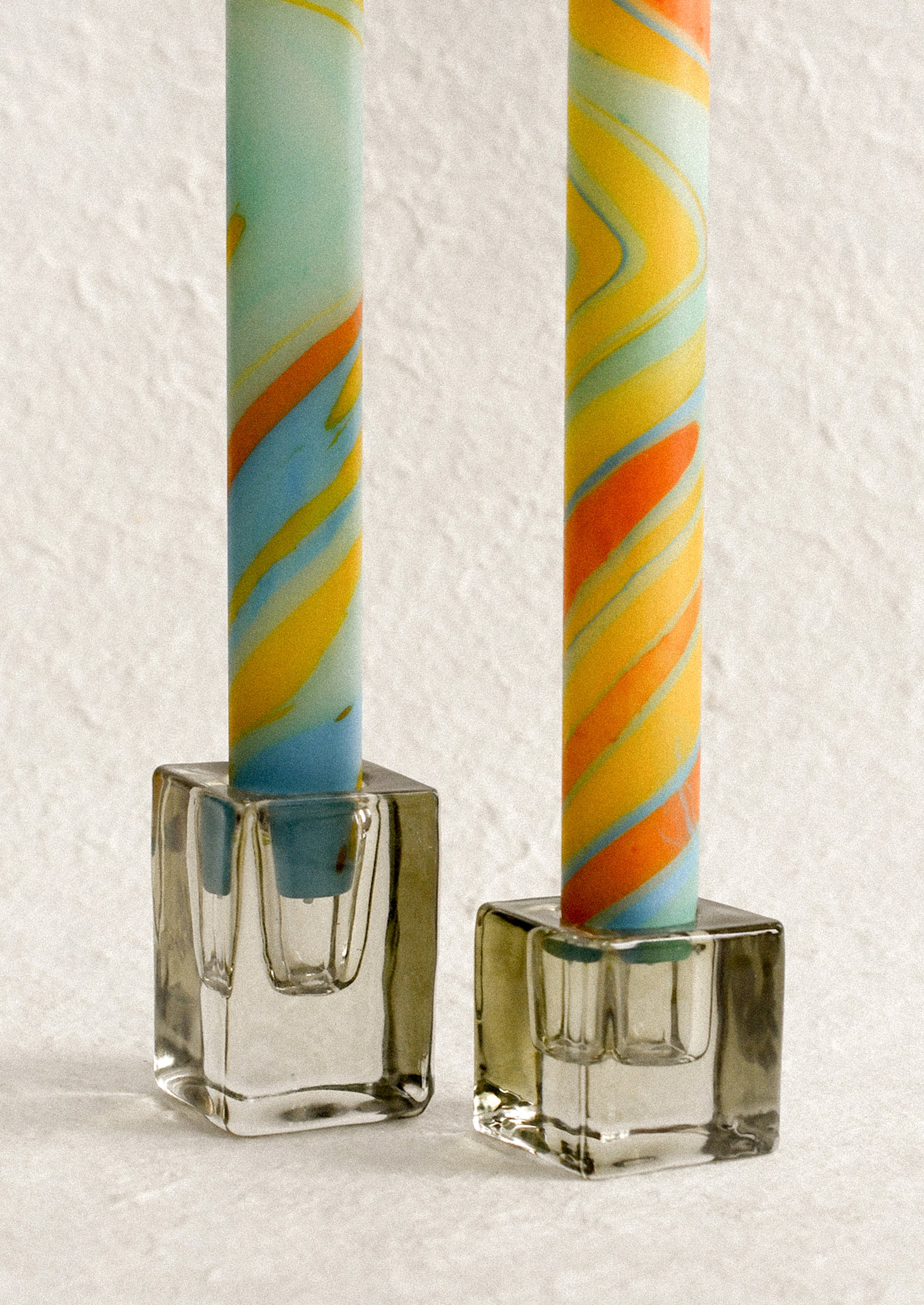 Slab glass candleholders holding multicolor taper candles.