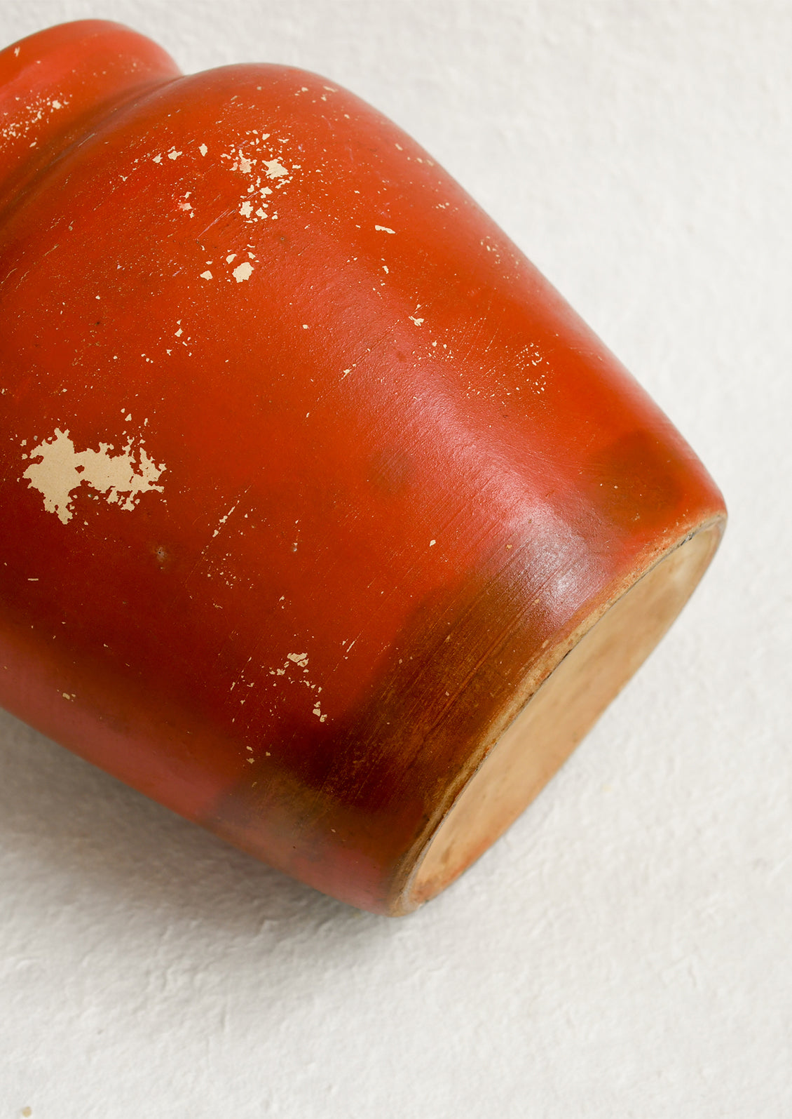 An antique cookie jar in red with chippy floral painted design.