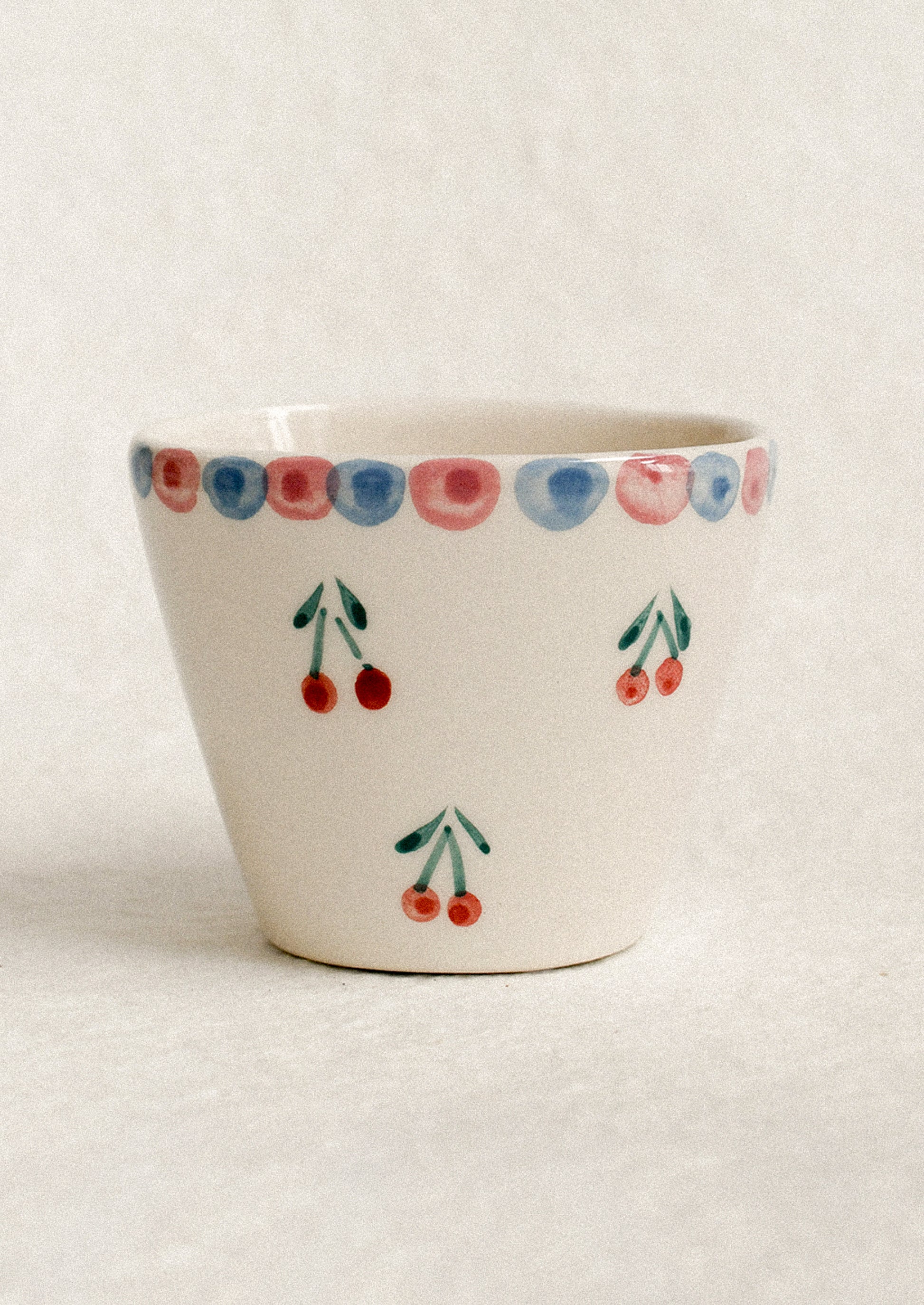A small hand painted cup with cherry motif.