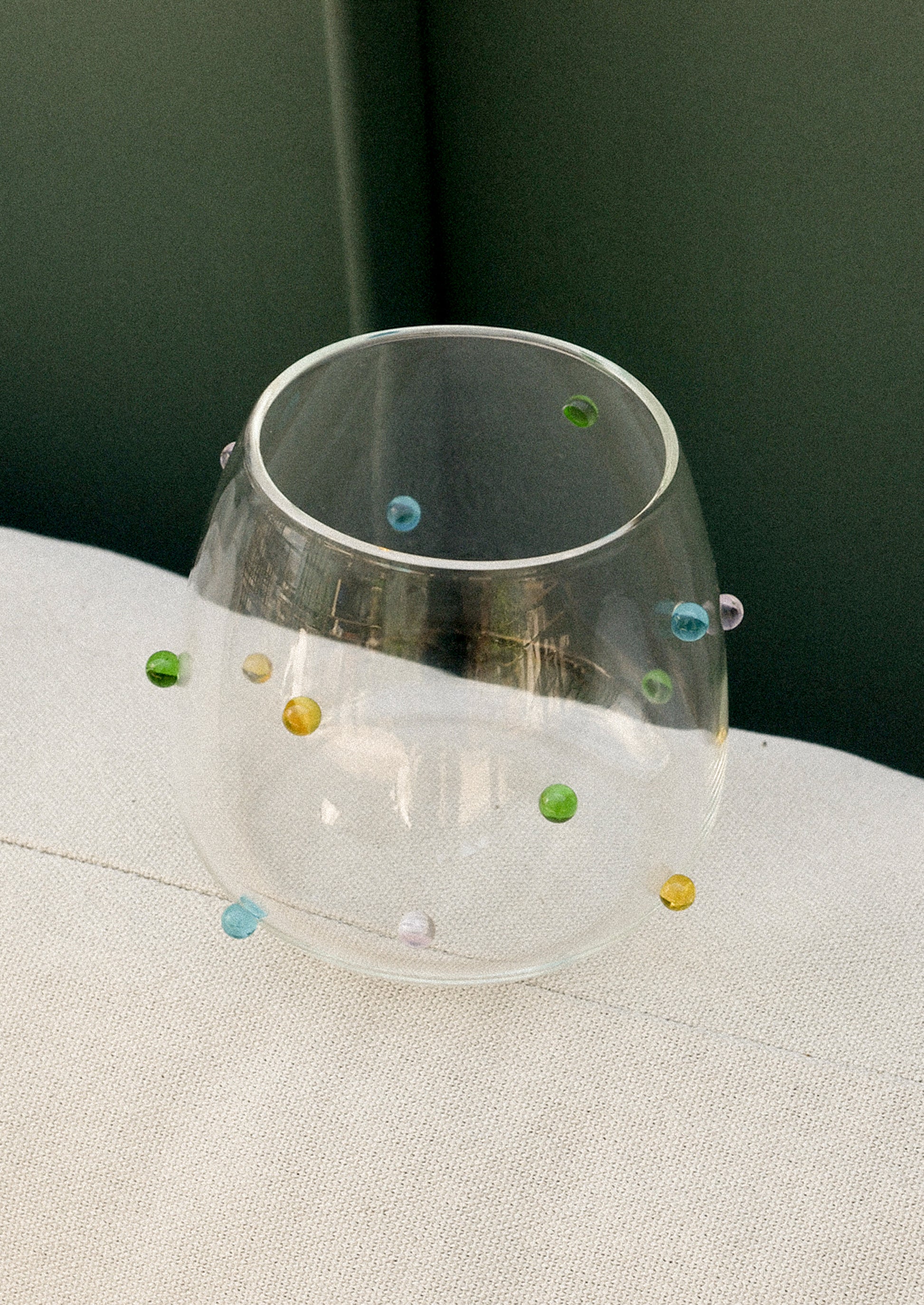 A clear glass tumbler with colorful raised "dots" on outside of glass.