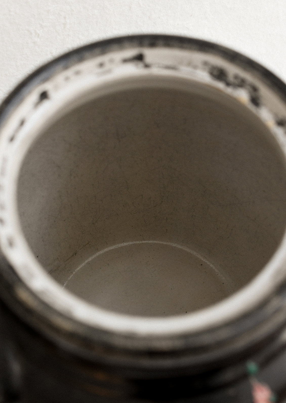 A vintage lidded crock in black with hand painted hollyhock pattern in pink and yellow.