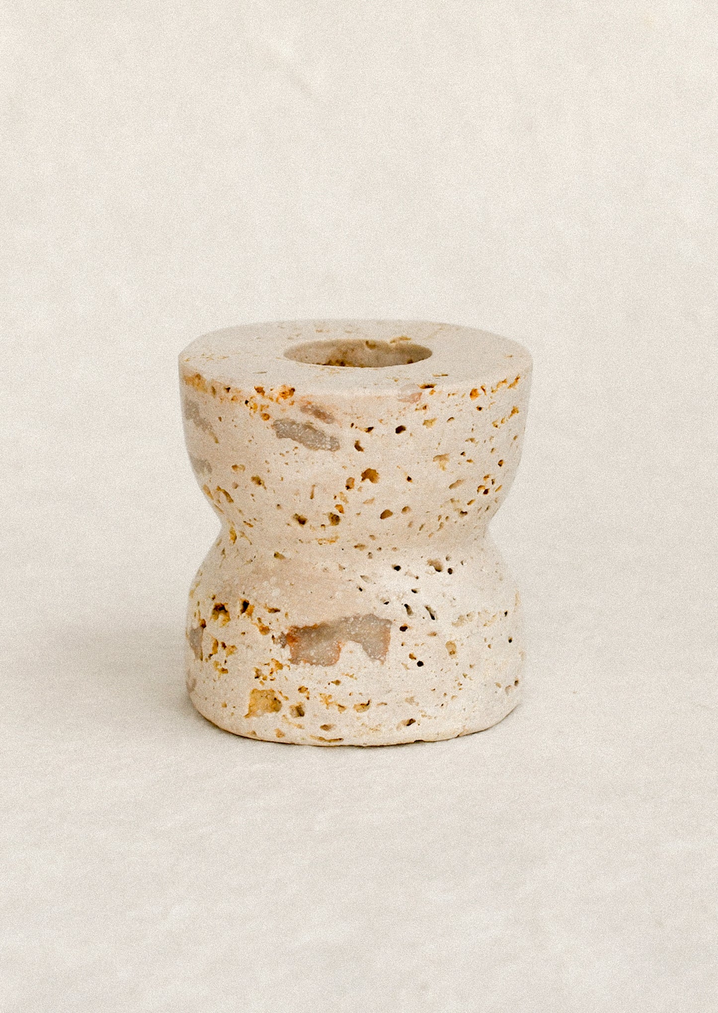 A natural travertine taper candle holder in short height.