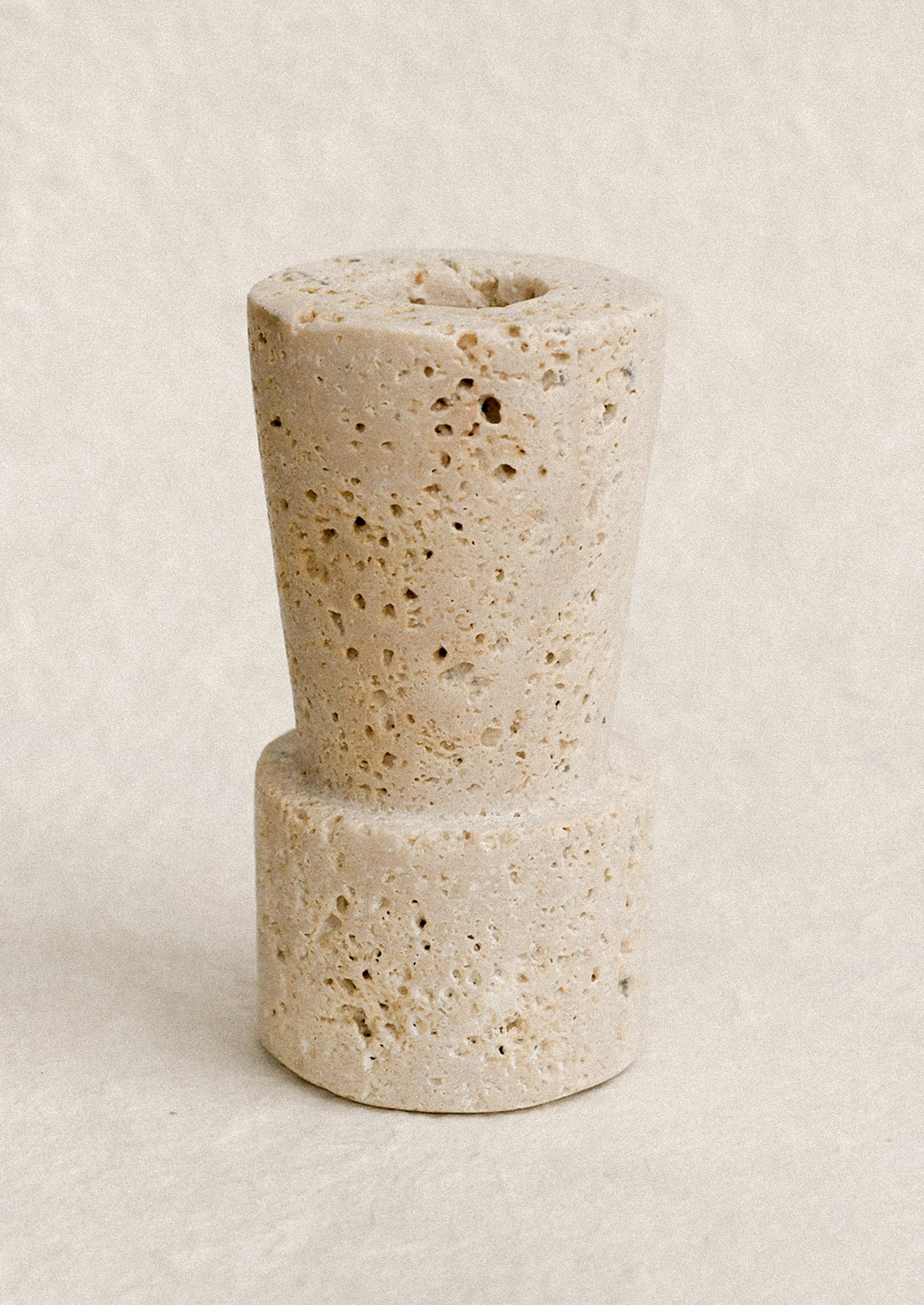 A natural travertine taper candle holder in tall height.