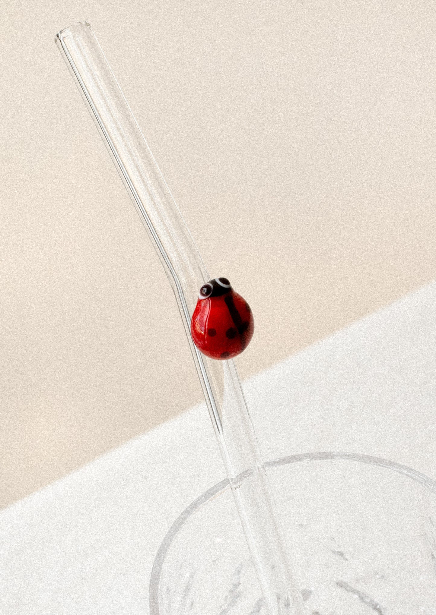 A clear glass straws with bent shape, with lampwork ladybug figurine.