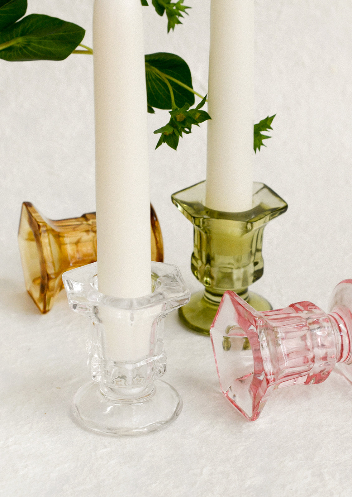 Footed glass candle holders in assorted colors.