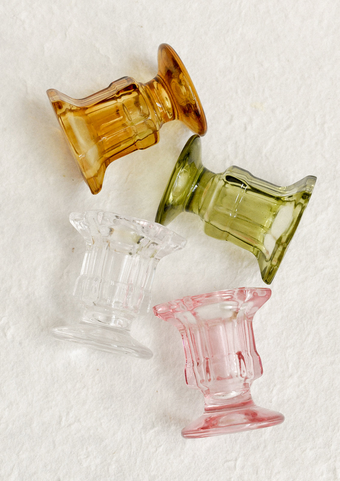 Footed glass candle holders in assorted colors.