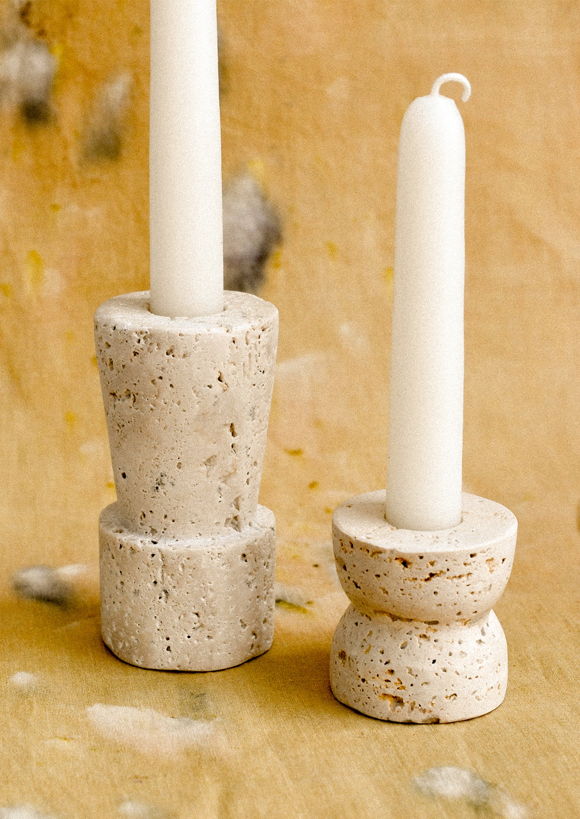 A pair of travertine candle holders with geometric shapes, in two height options.