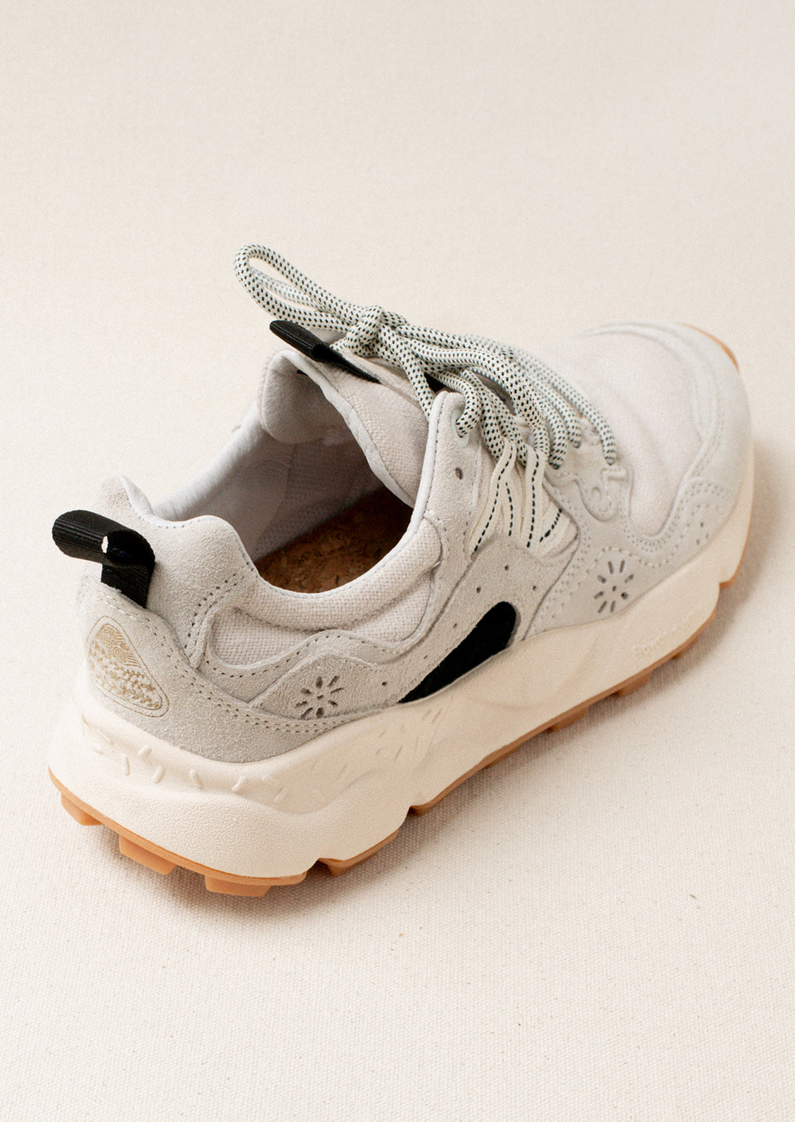 A pair of sporty sneakers in neutral colors with flower cutout detailing.