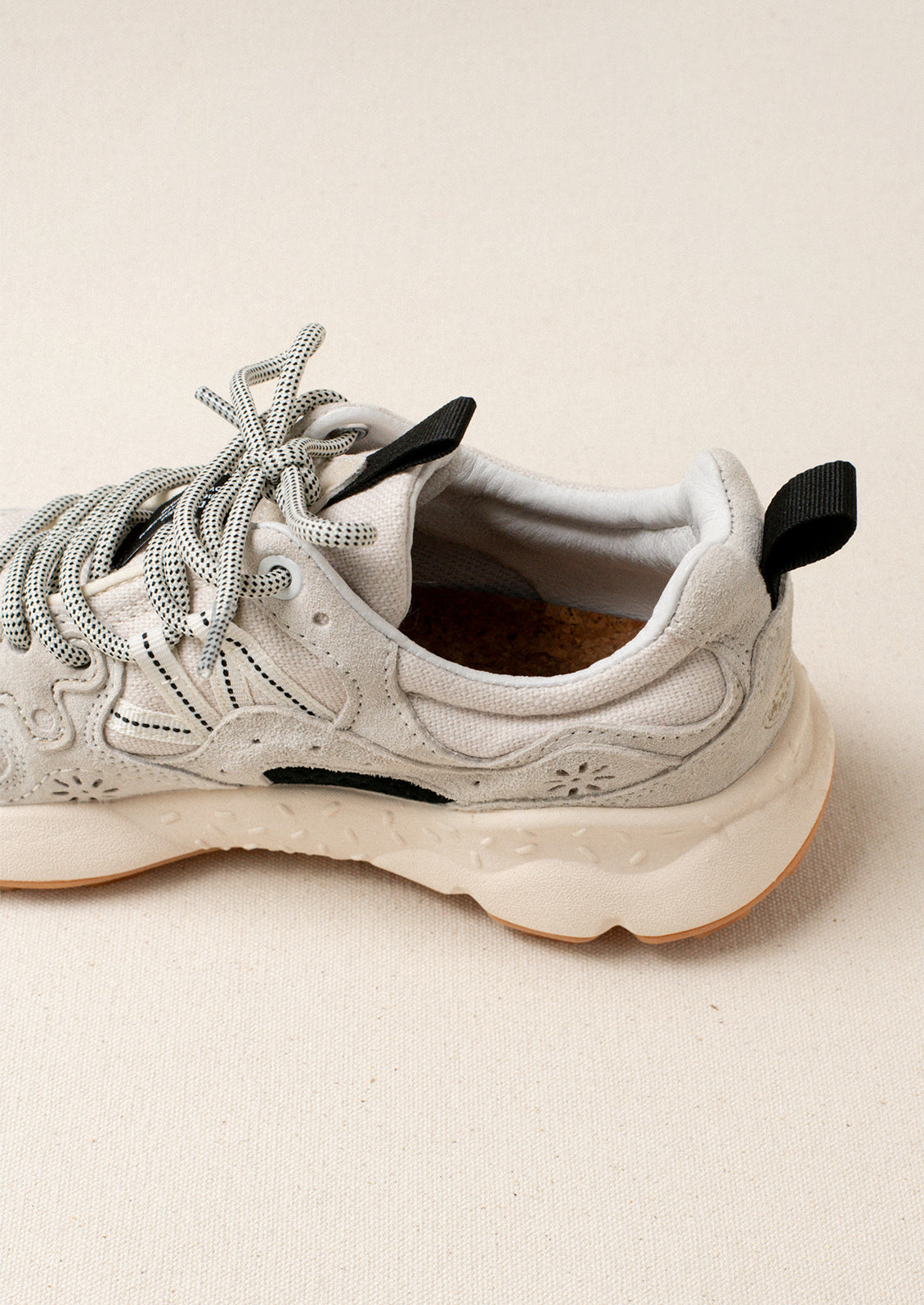A pair of sporty sneakers in neutral colors with flower cutout detailing.