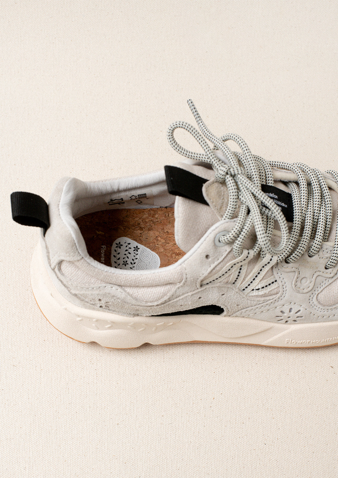 A pair of sporty sneakers in neutral colors with flower cutout detailing.