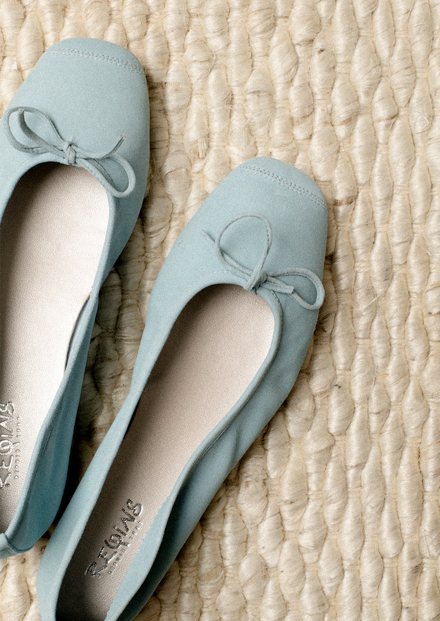 A pair of suede ballet flats in light blue.