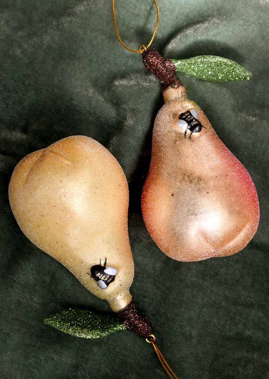 Two pear-shaped ornaments on a green fabric background