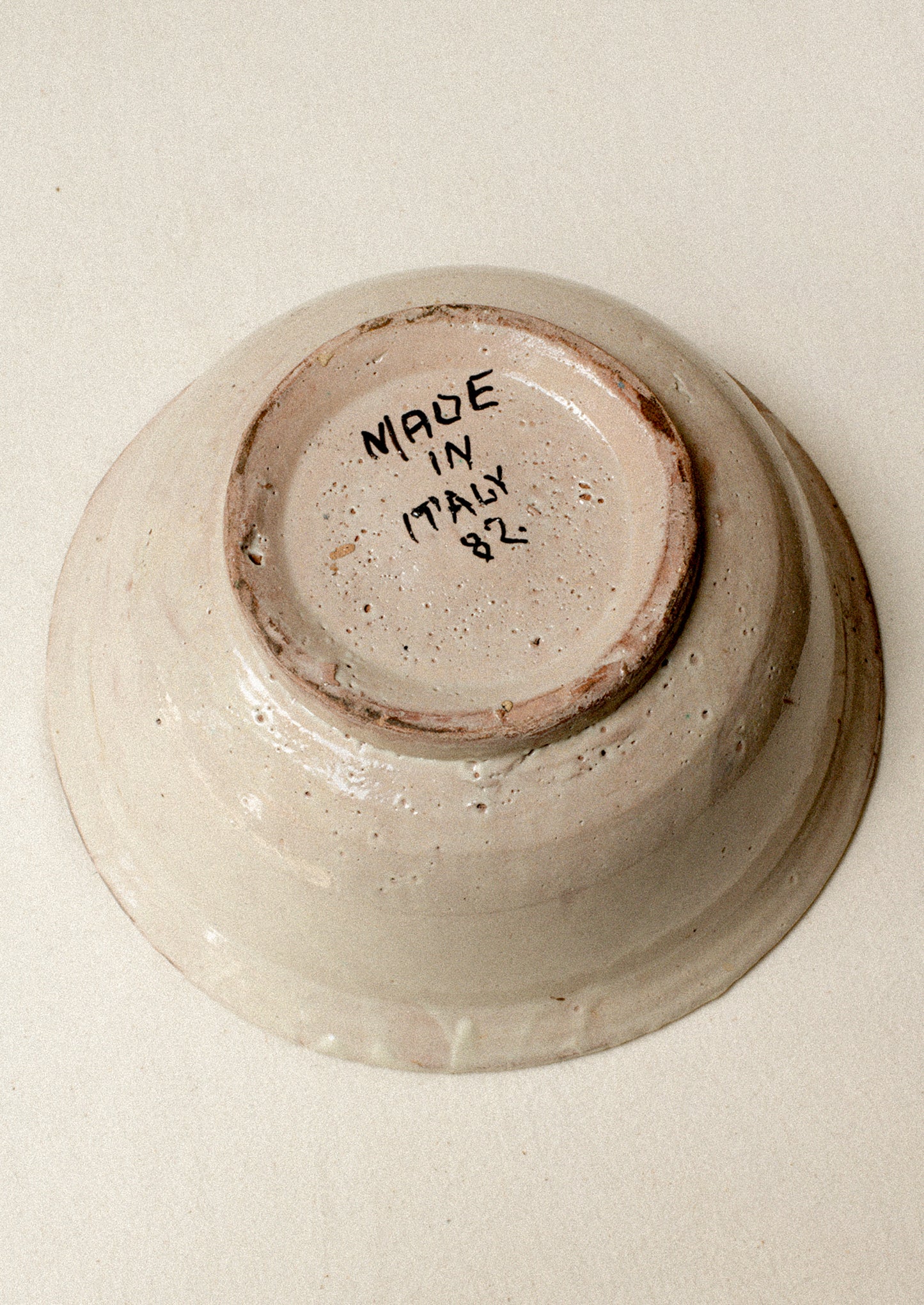 An antique ceramic bowl with "Made in Italy 82" handwritten on bottom.