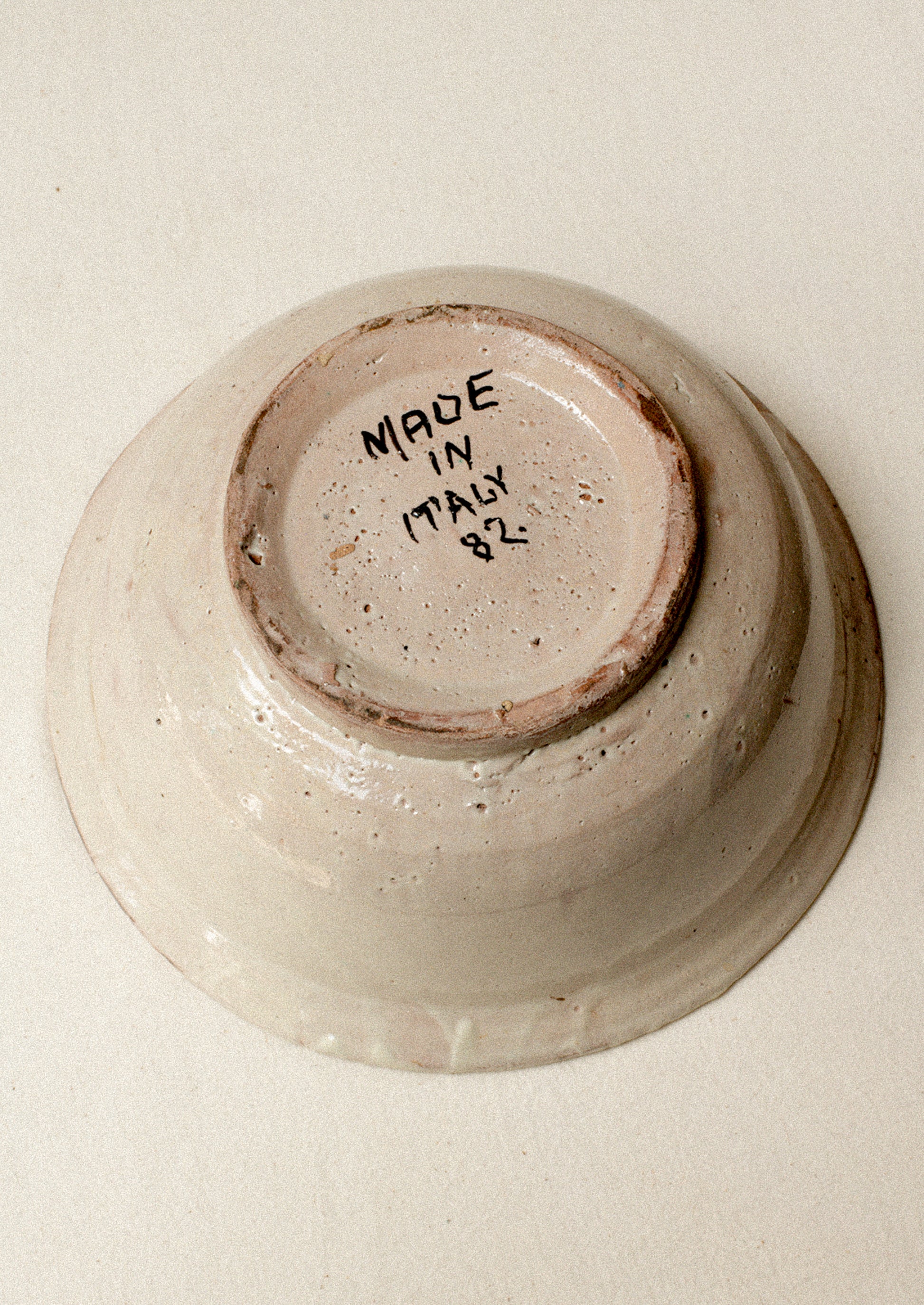 An antique ceramic bowl with "Made in Italy 82" handwritten on bottom.