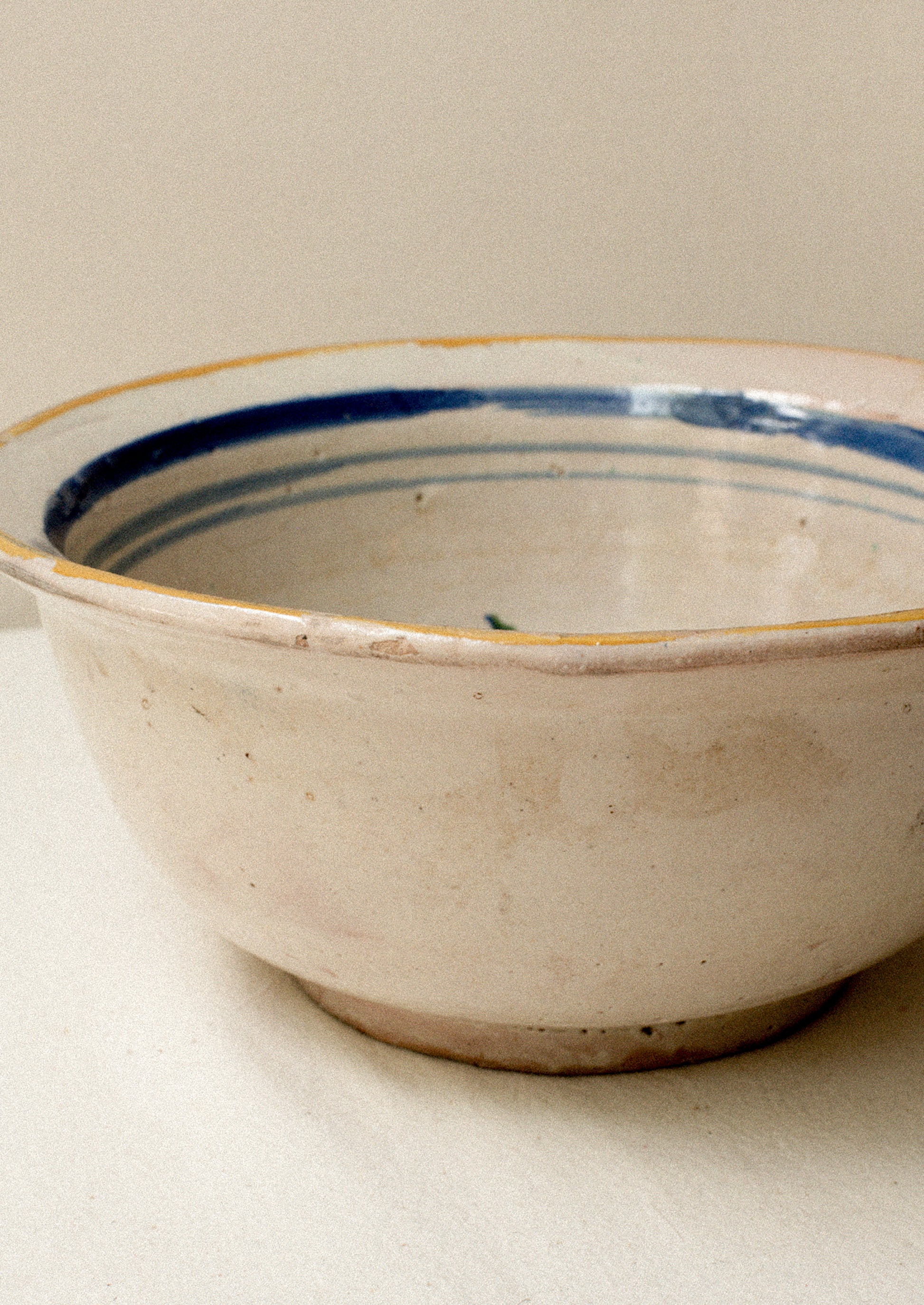 An antique ceramic serving bowl with painted blue rim.