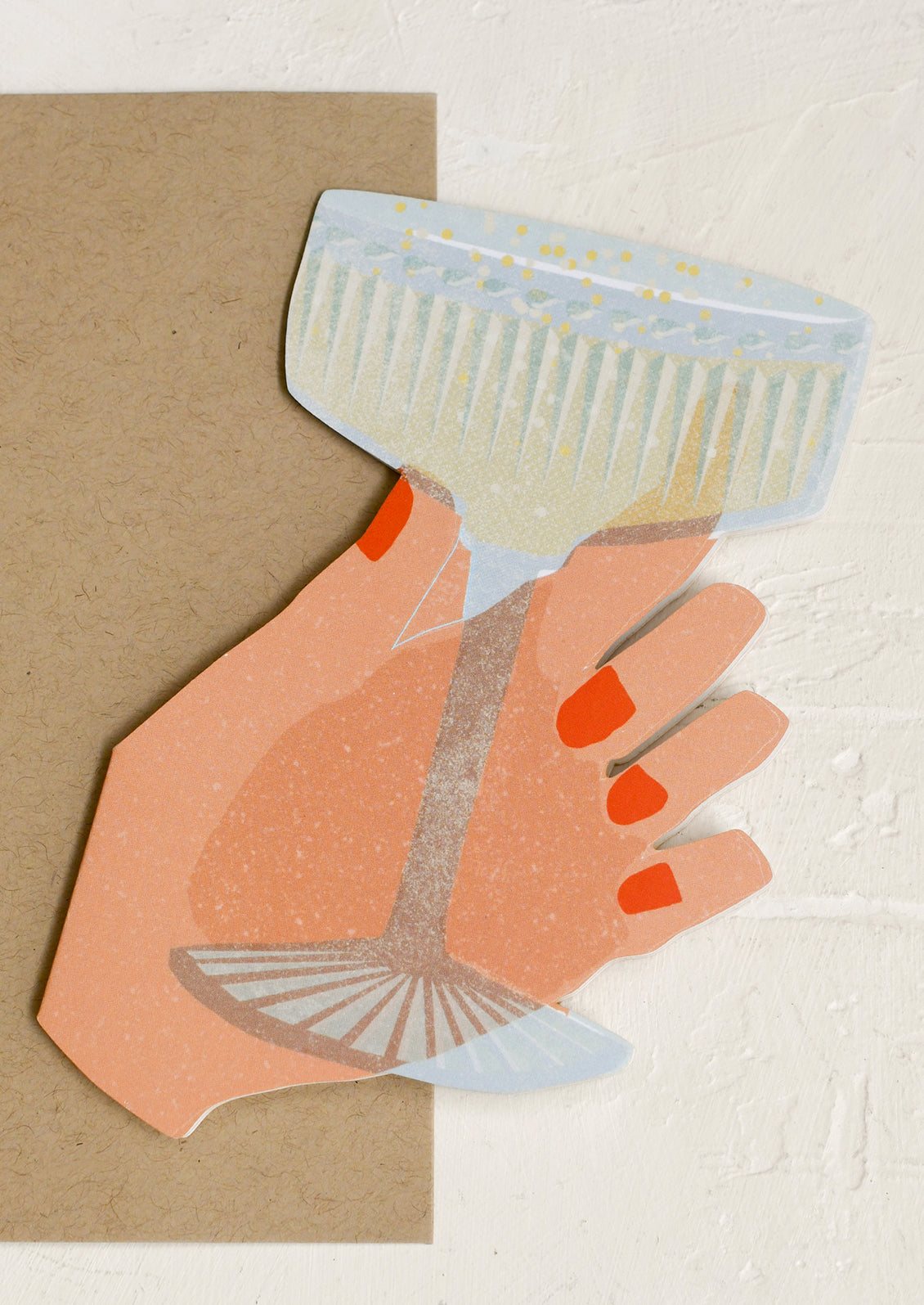 A die cut greeting card in the shape of a hand holding a coupe glass.