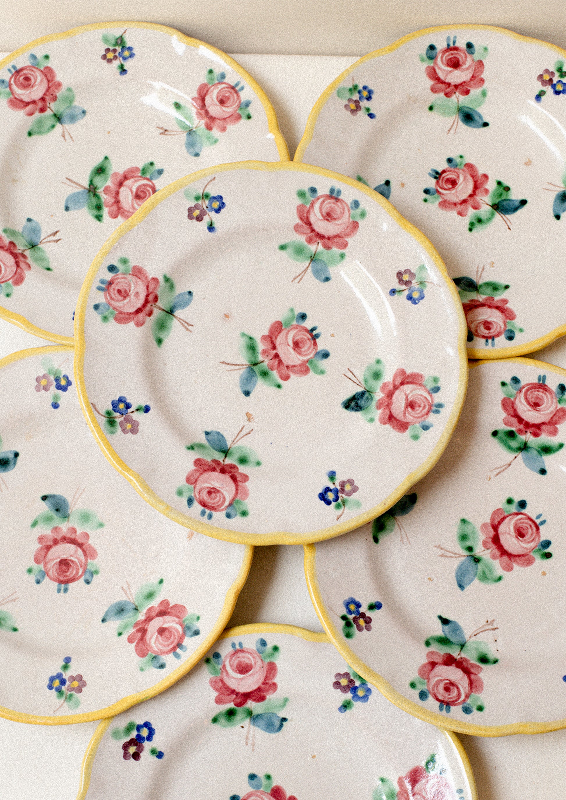 A set of vintage Italian hand painted floral plates with yellow rim.