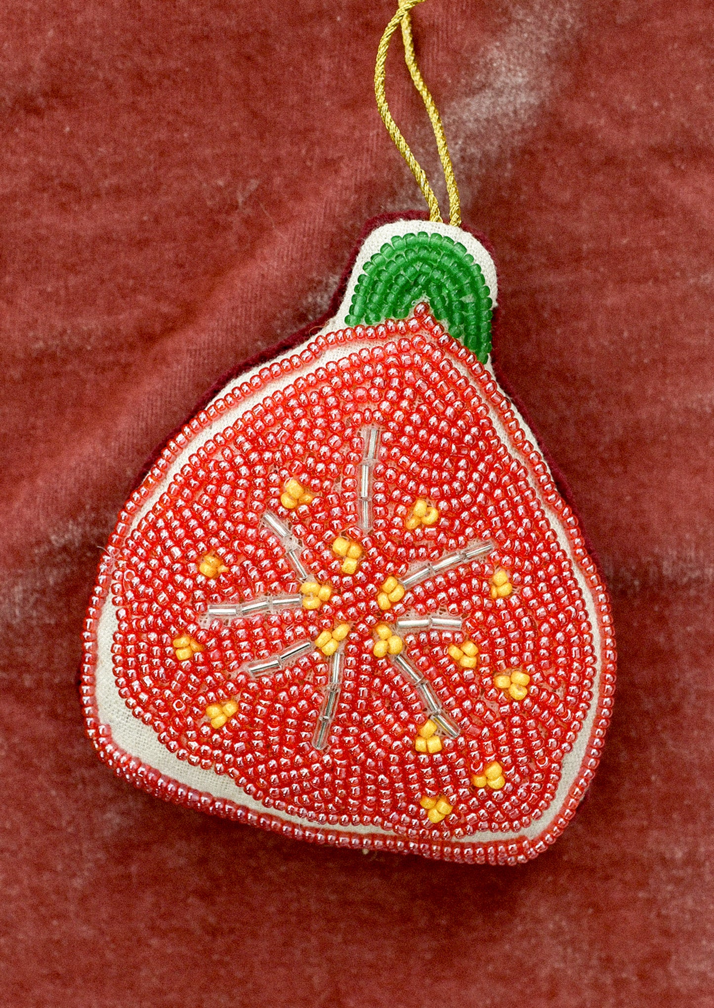Decorative beaded fig ornament on a red background