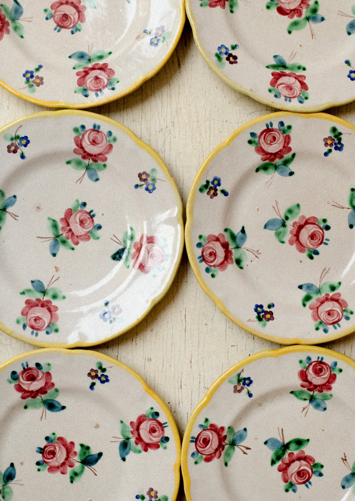 A set of vintage Italian hand painted floral plates with yellow rim.