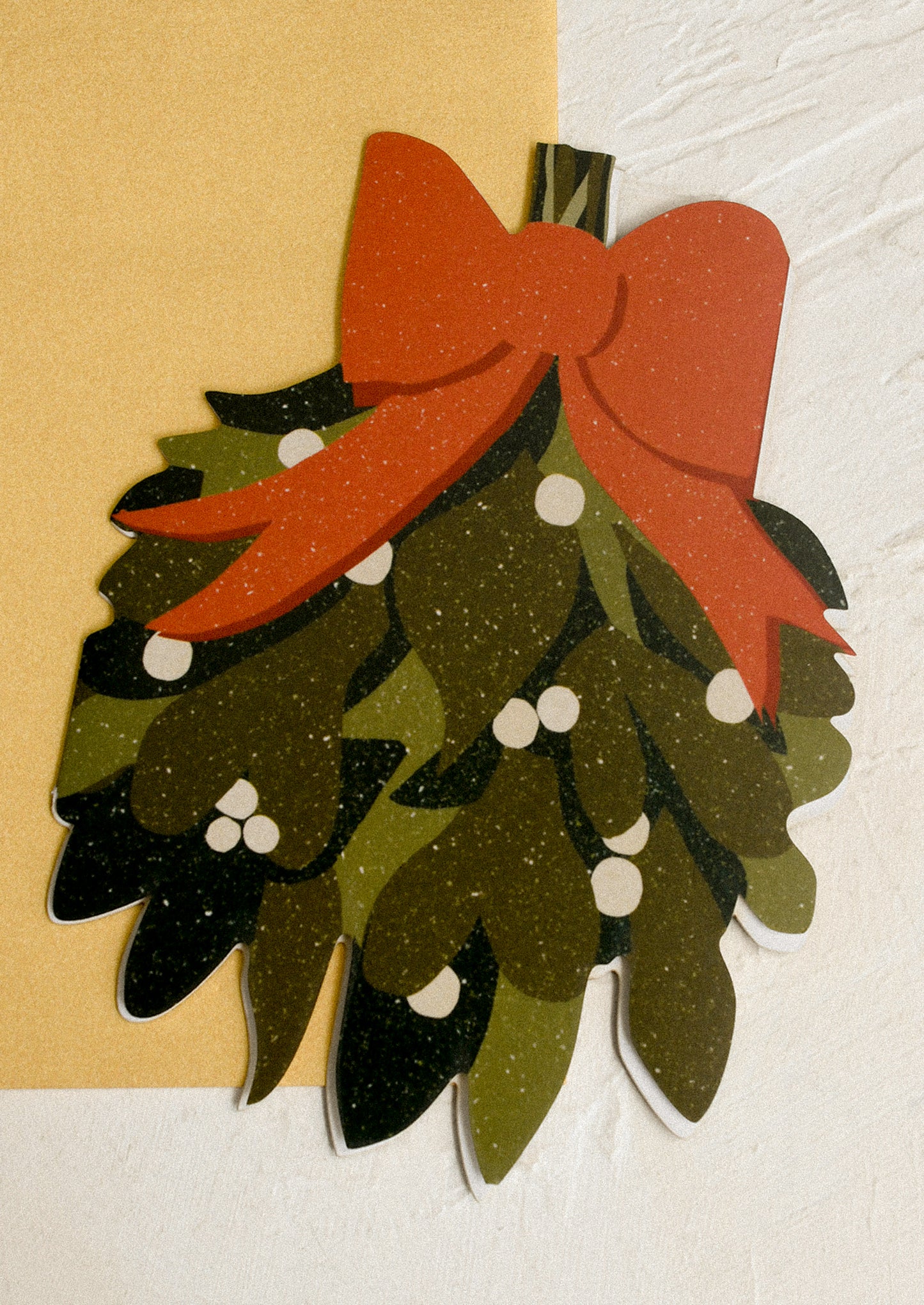A holiday greeting card in diecut mistletoe shape, with gold envelope.