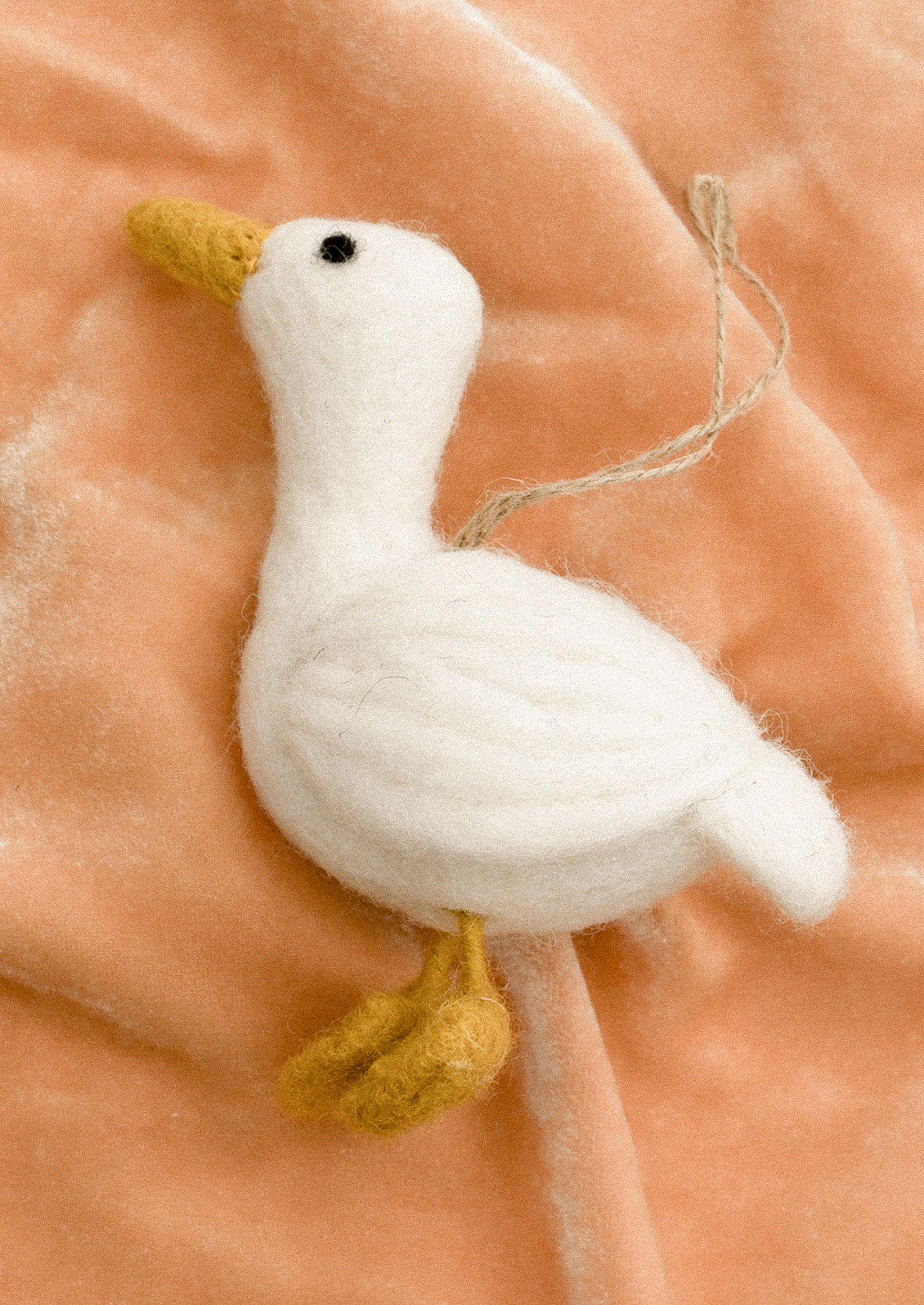 A white felt bird ornament with yellow feet and beak.