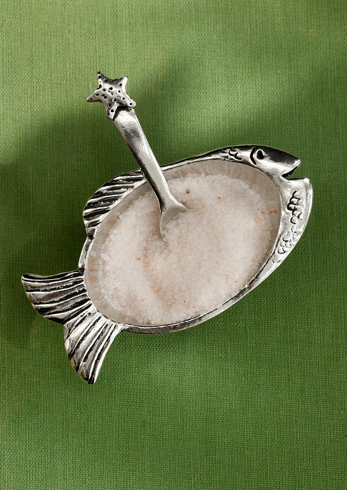 Decorative fish-shaped spoon rest on a green background
