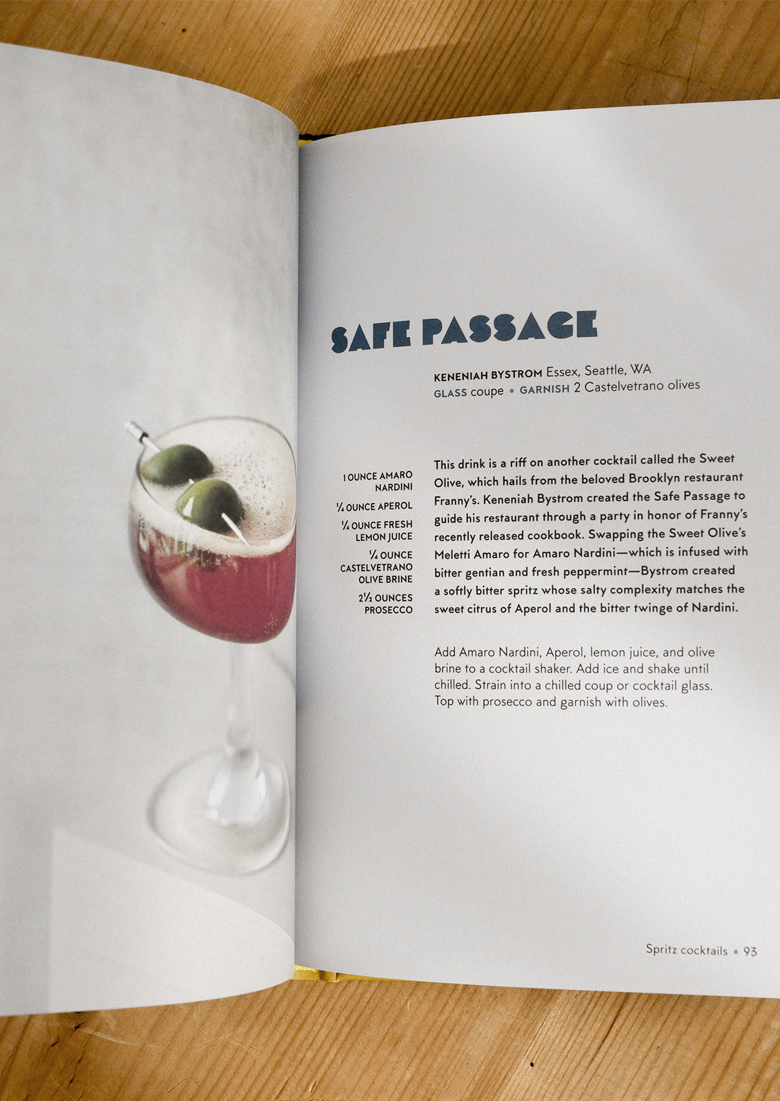 Open book with a cocktail recipe titled 'Safe Passage' on a wooden surface