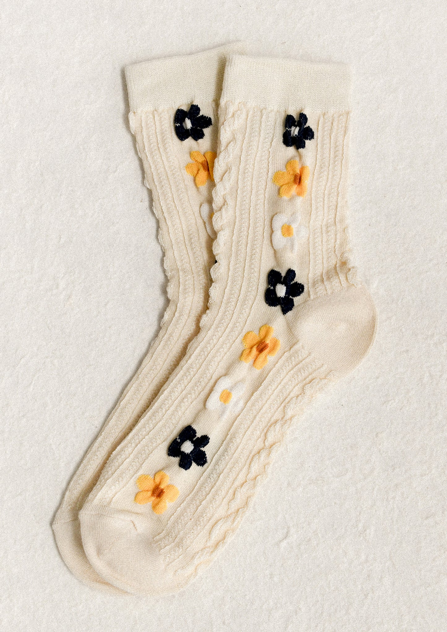 A pair of cream socks with yellow, navy and white floral pattern.